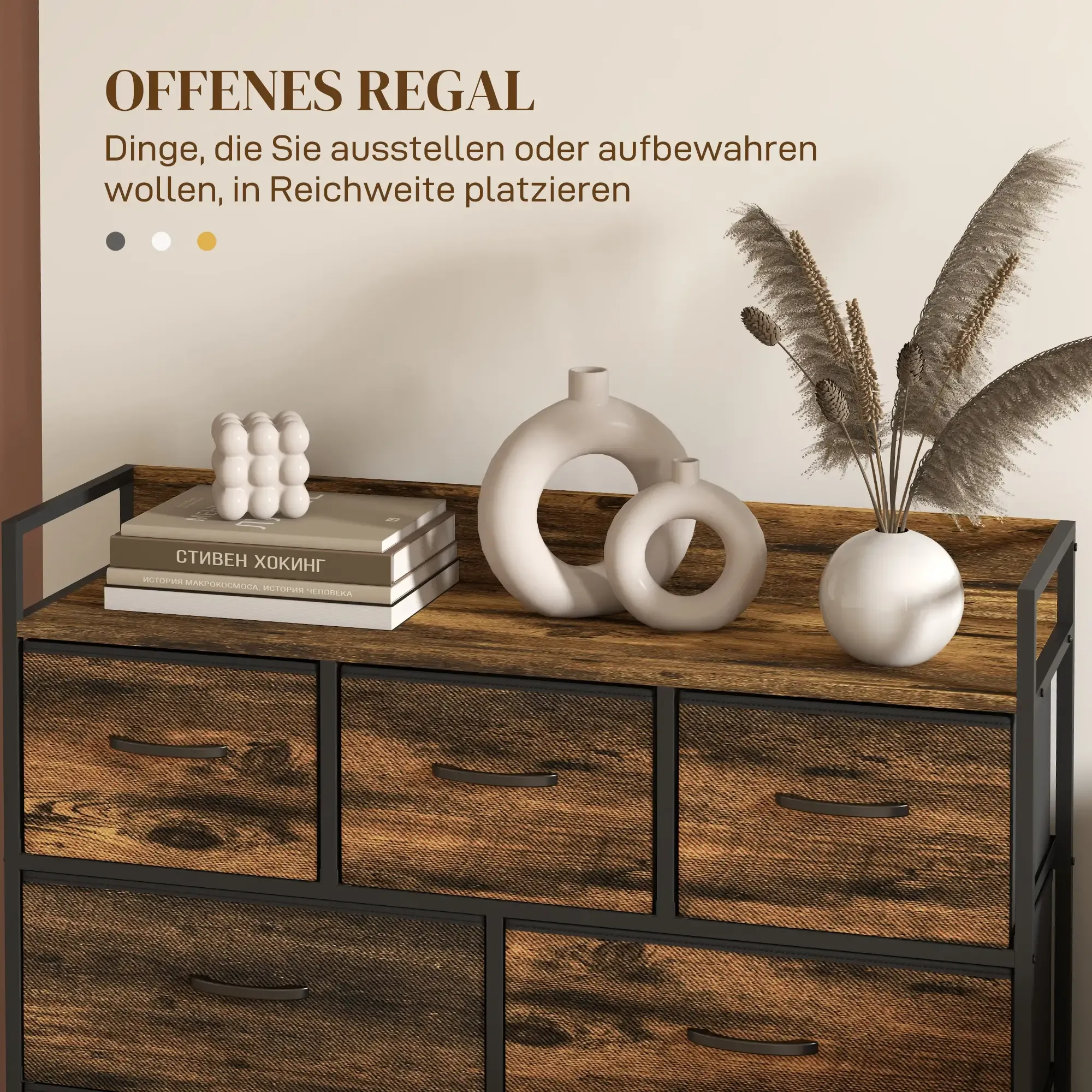 Eine Kommode mit Holzplatte und Schubladen, Vasen und Büchern oben, schwarzem Metallrahmen, vor einer hellbeigen Wand.