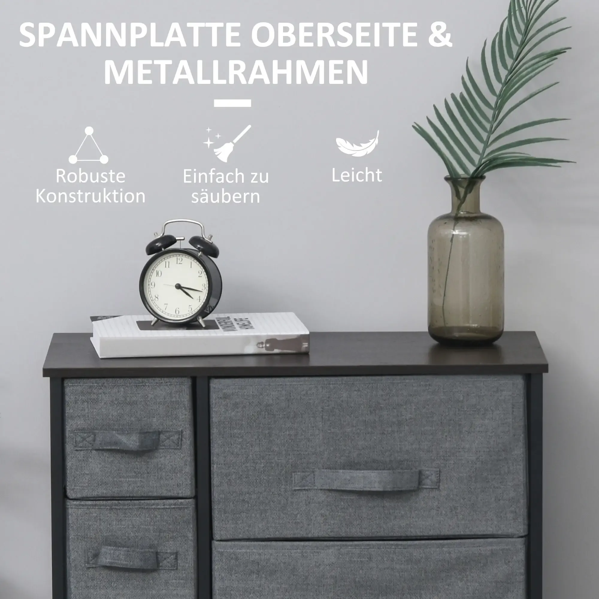 Kommode mit Wecker, Buch und Vase mit Pflanze.