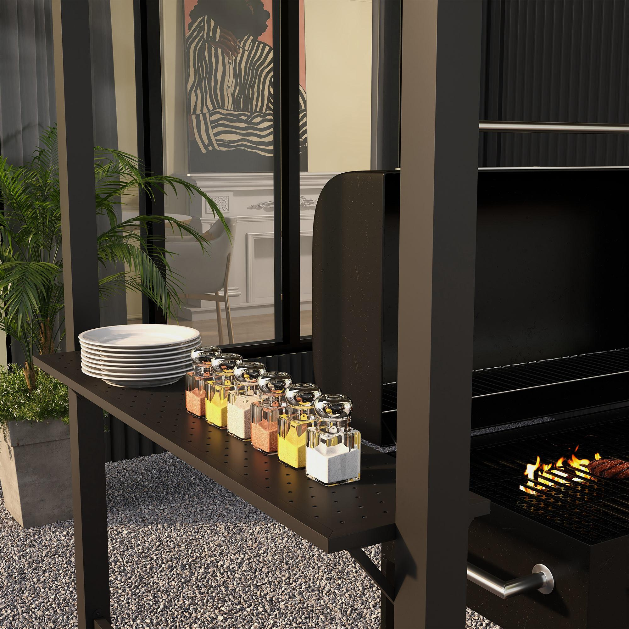Outdoorgrill mit schwarzem Tisch. Teller, Gewürzgläser und Grill mit Essen sind sichtbar. Garten im Hintergrund.