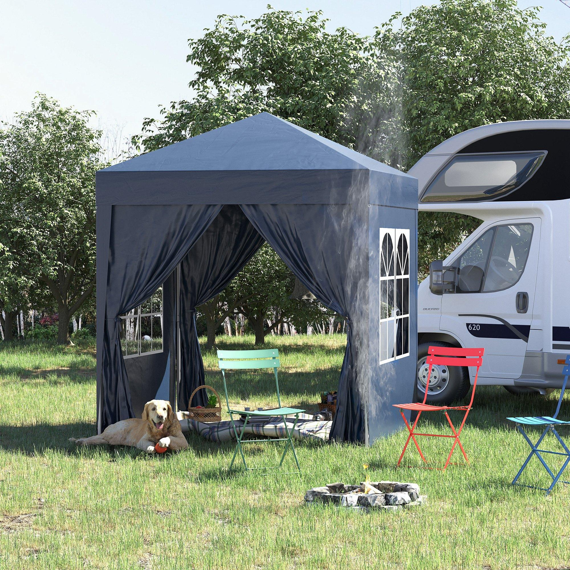 Ein blauer Pavillon auf Gras, mit Hund, Stühlen und einem Wohnmobil im Hintergrund.