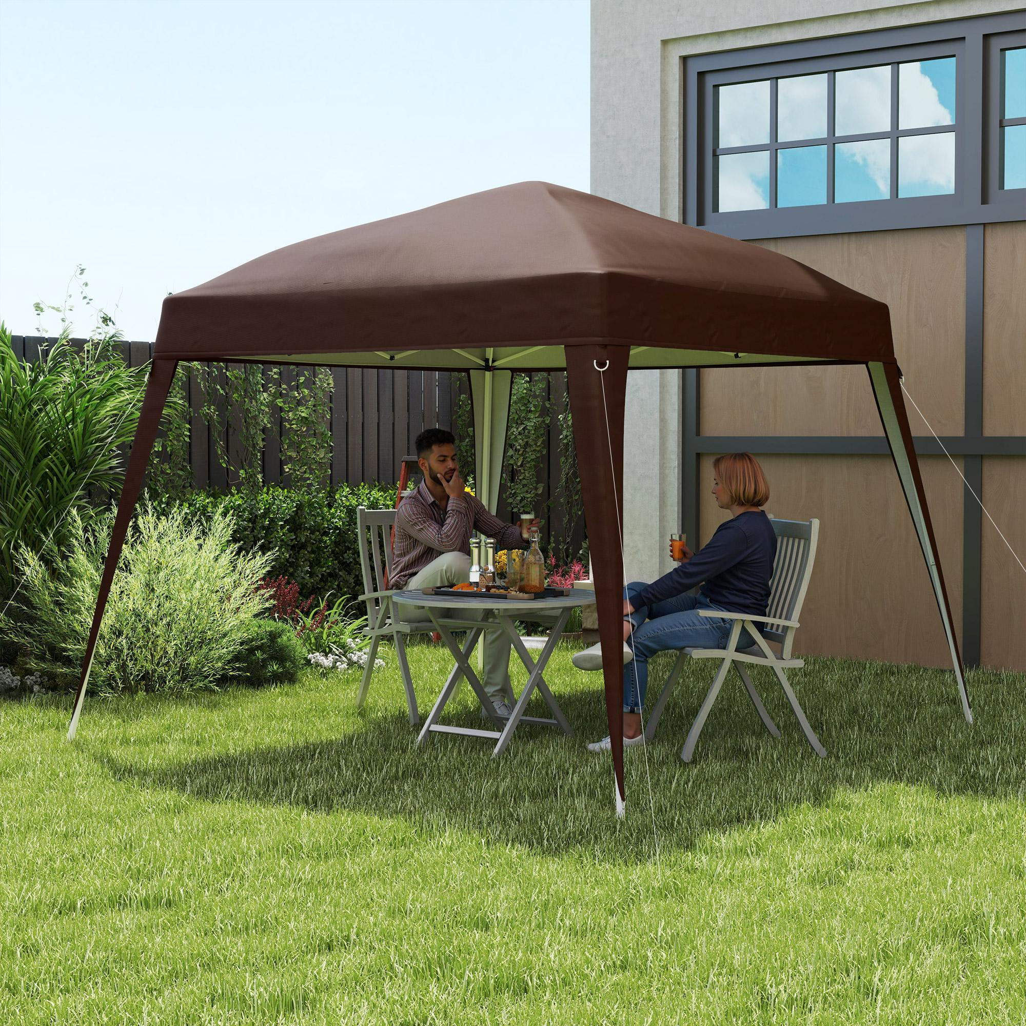 Zwei Personen sitzen unter einem braunen Zelt an einem Tisch in einem grünen Garten.