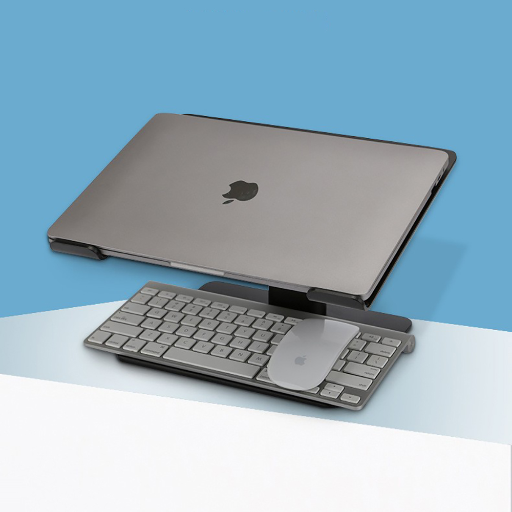 Ein Laptop, eine Tastatur und eine Maus stehen auf einem Ständer vor blau-weißem Hintergrund.