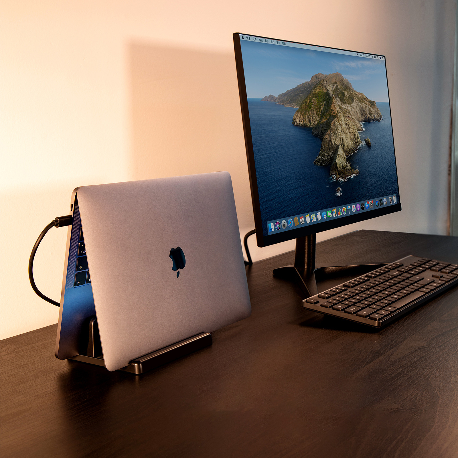 Ein Laptop ist an einen Monitor und eine Tastatur angeschlossen. Der Laptop steht auf einem Ständer mit schwarzem Schreibtisch.