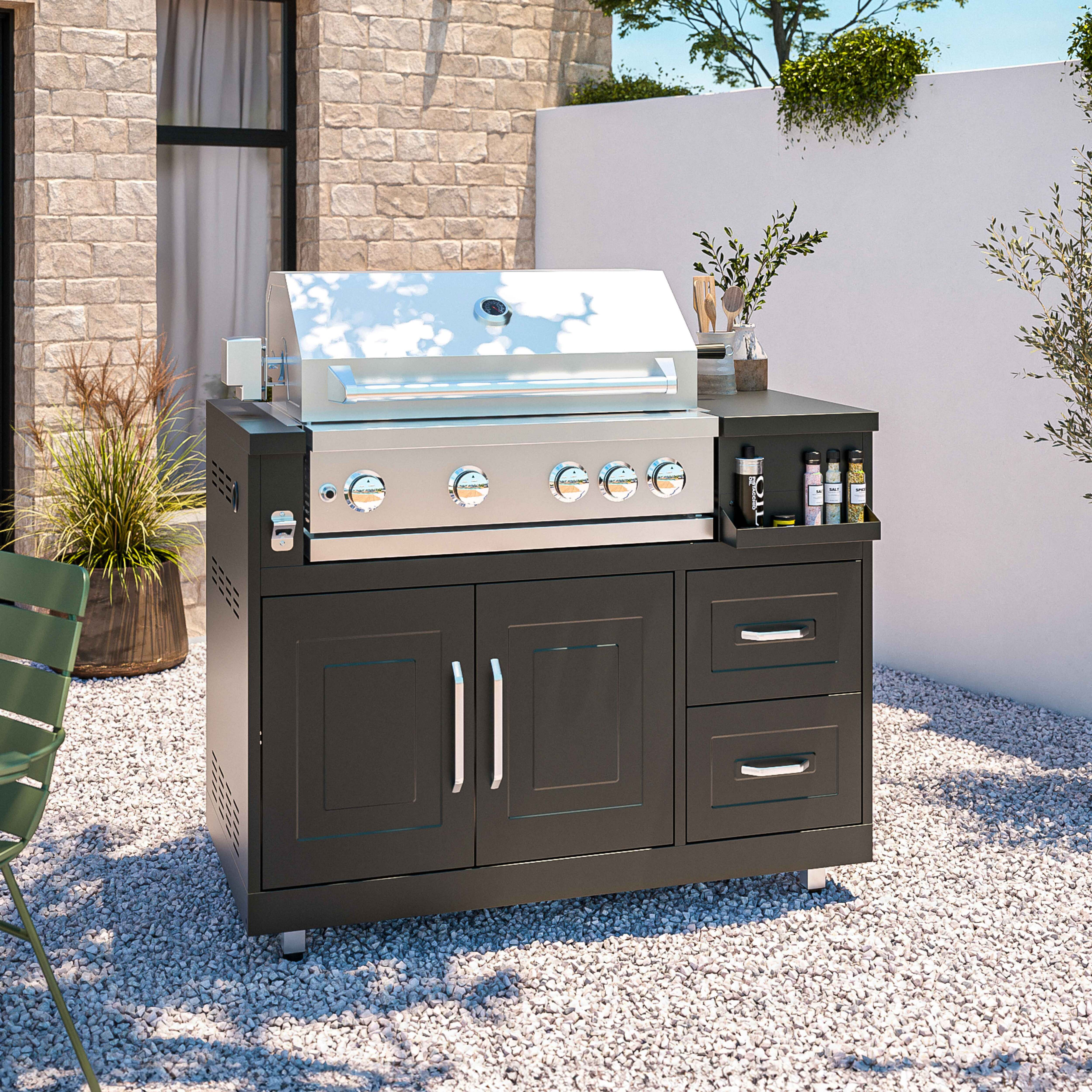 Outdoorküche mit Grill, Schubladen und Schränken. Auf Kiesoberfläche.