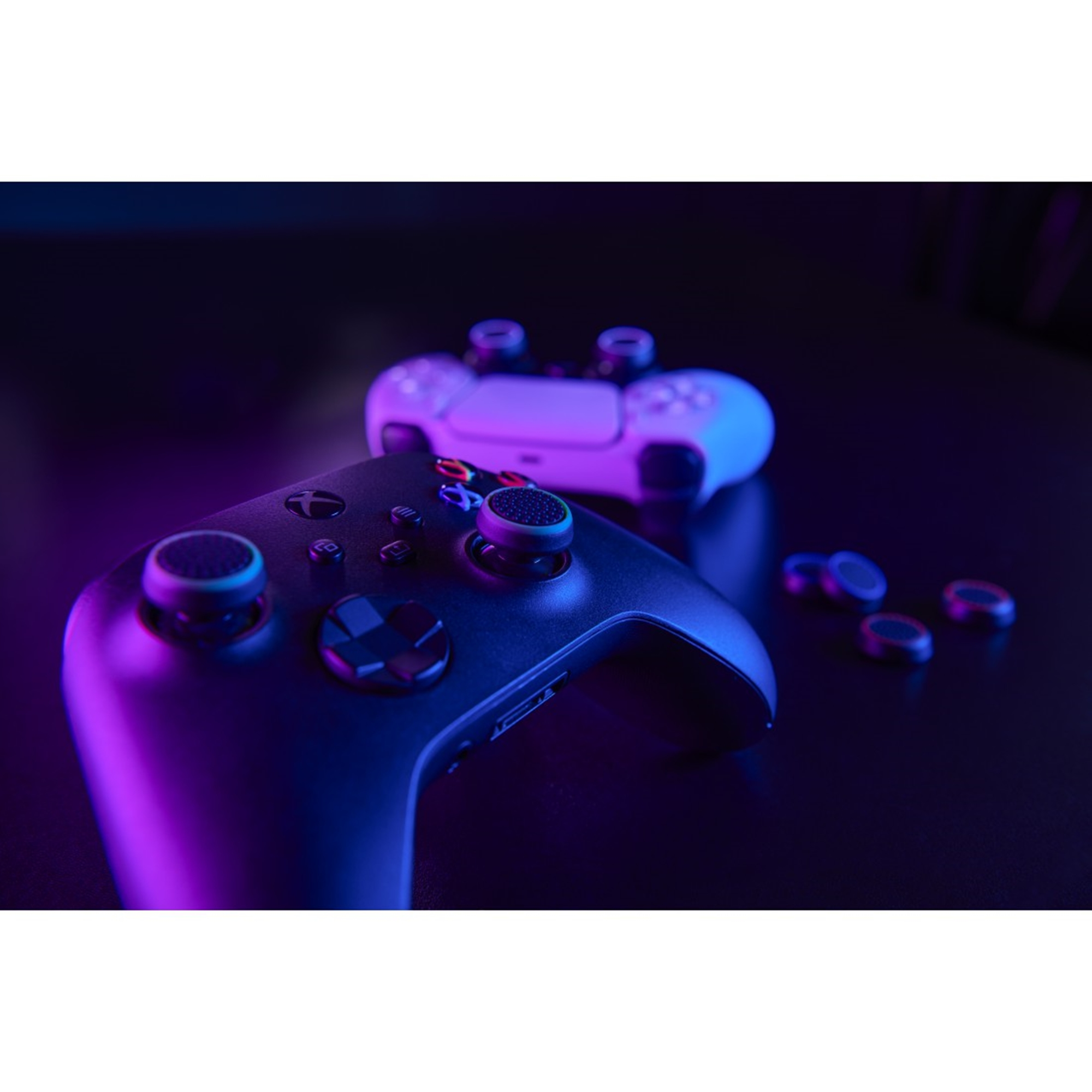 Zwei Gamecontroller mit verschiedenfarbigen Knöpfen und Sticks auf dunkler Oberfläche mit lila Beleuchtung.
