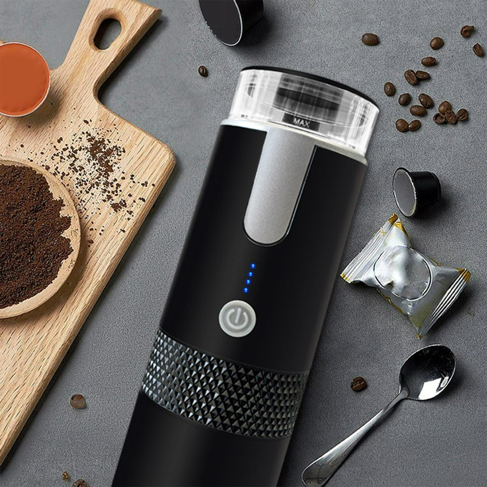 Ein tragbarer Kaffeezubereiter mit Kaffeebohnen, -pulver und Zubehör auf grauer Oberfläche.