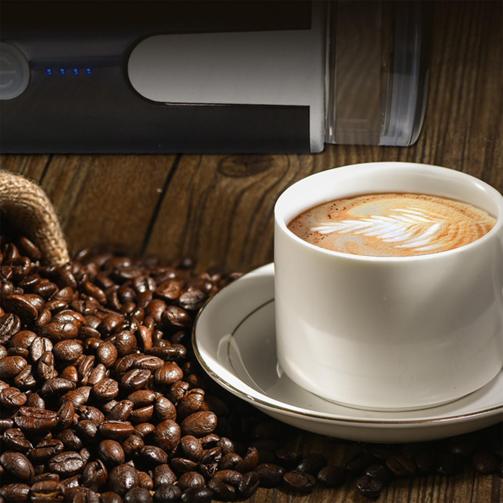 Eine Tasse Kaffee mit Latte Art auf einer weißen Untertasse, umgeben von Kaffeebohnen und Zubehör.