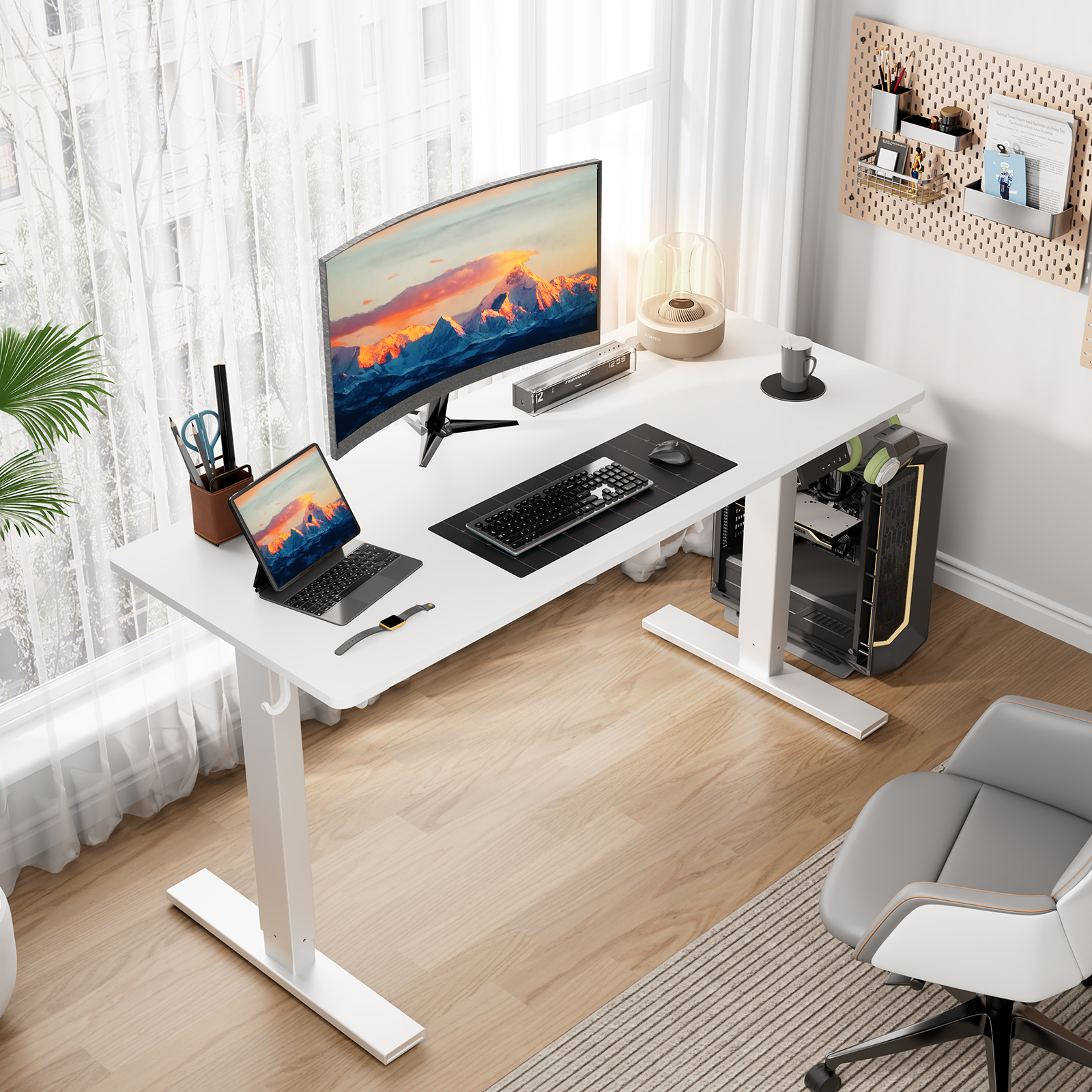 Een witte staande bureau met een monitor, laptop en accessoires in een thuiskantoor.