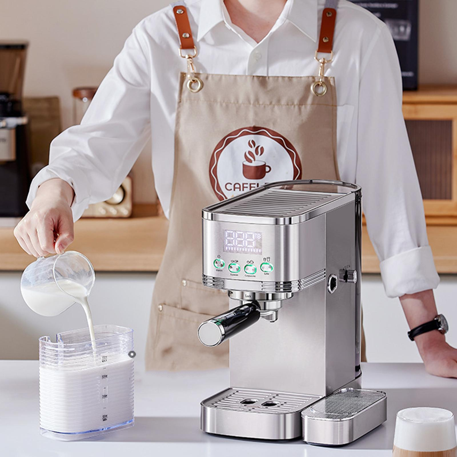 Person gießt Milch in einen Behälter, neben einer silbernen Espressomaschine.