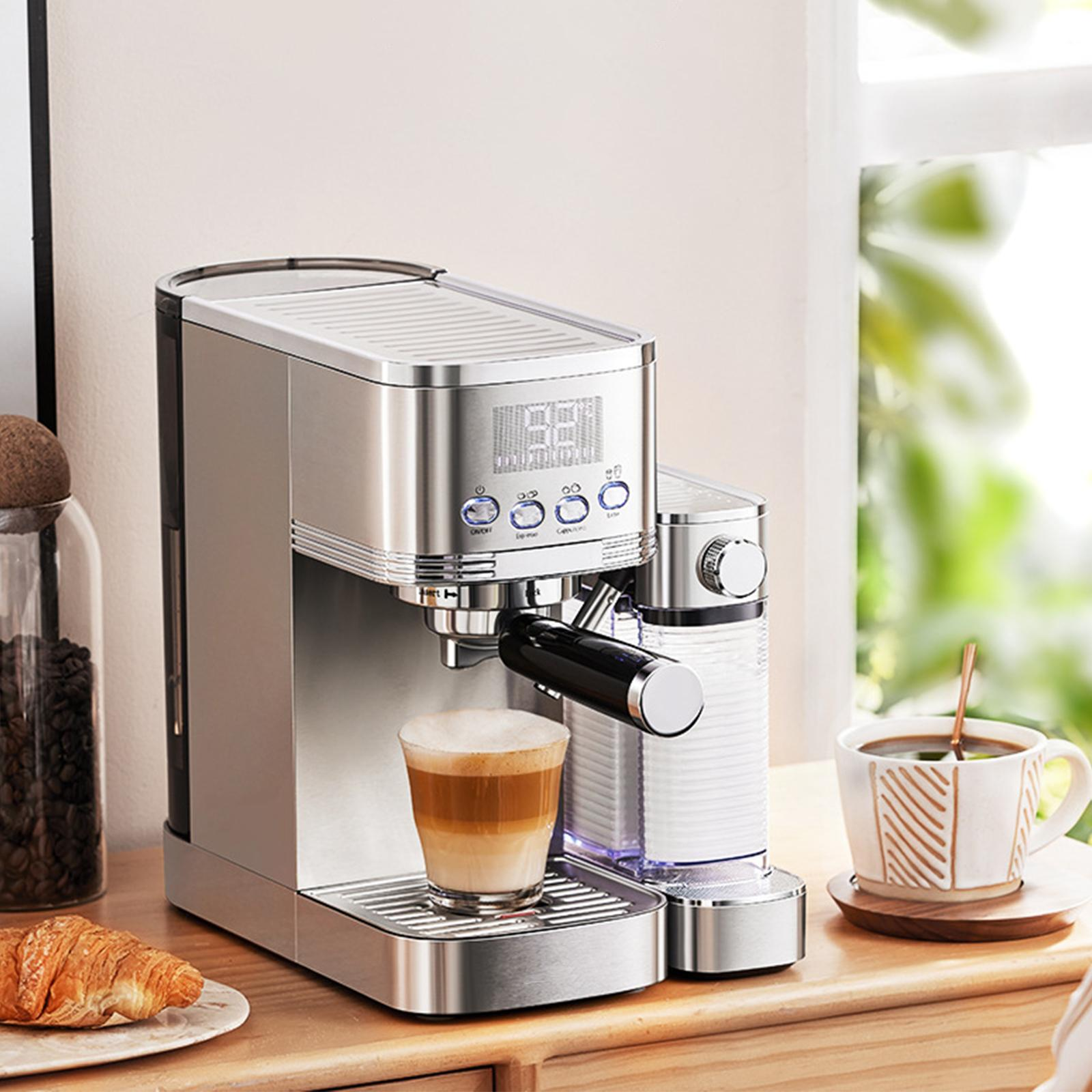 Eine silberne Espressomaschine mit Latte in einem Glas, einem Croissant und einer Tasse Kaffee auf einem Tisch.