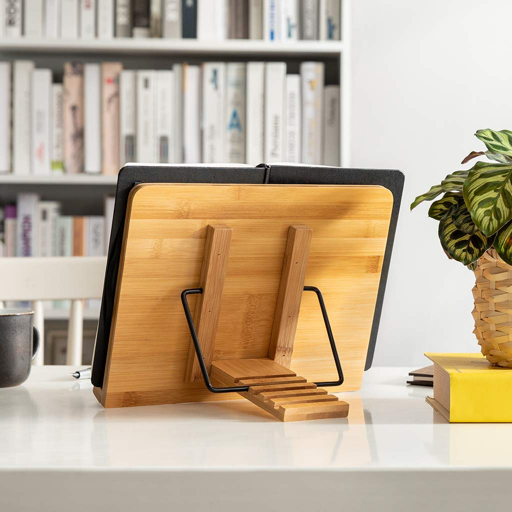 Buchständer aus Holz mit Buch, Schreibtisch, Regal mit Büchern und Pflanze im Hintergrund.