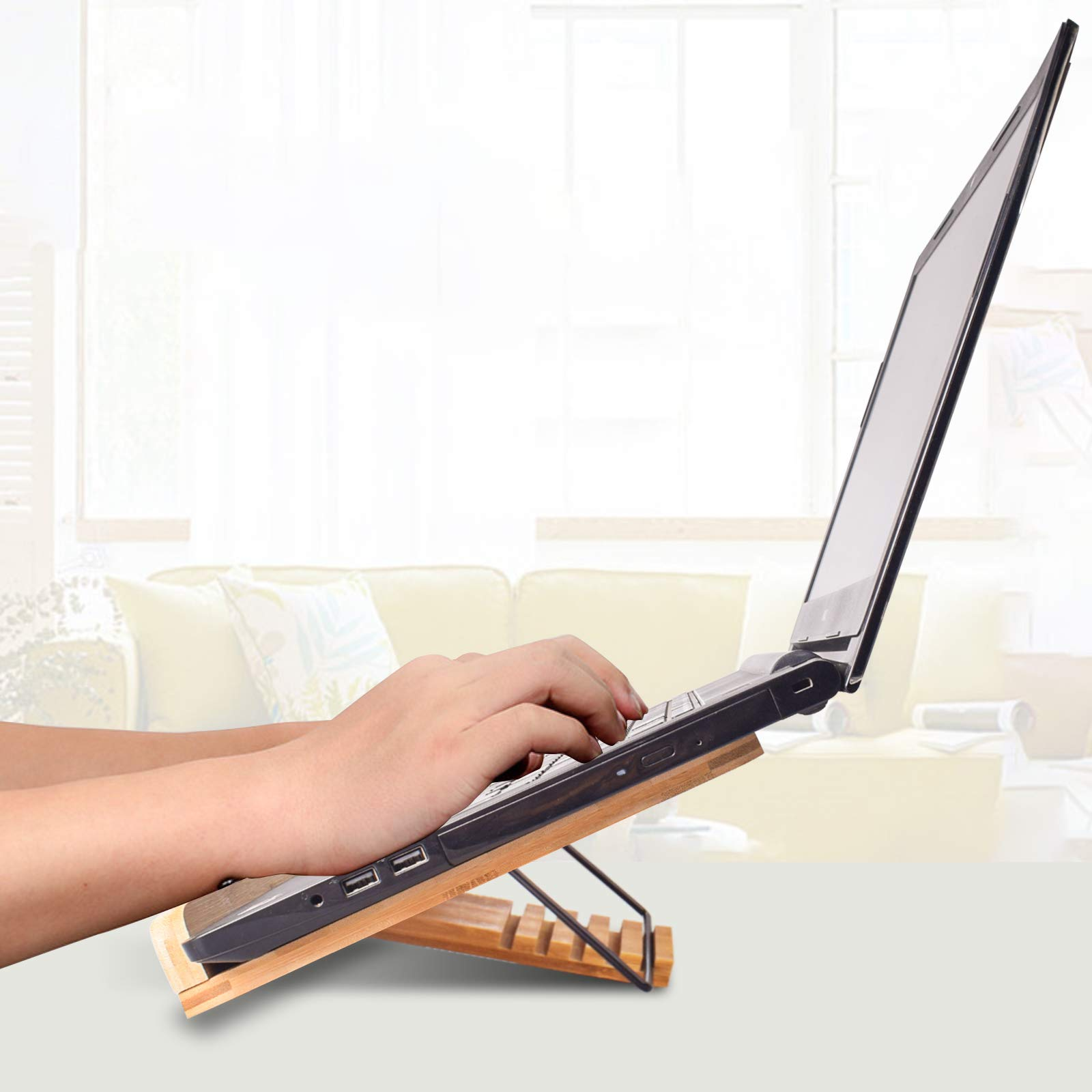 Ein Laptop steht auf einem Holzständer. Die Hände einer Person sind auf der Tastatur.