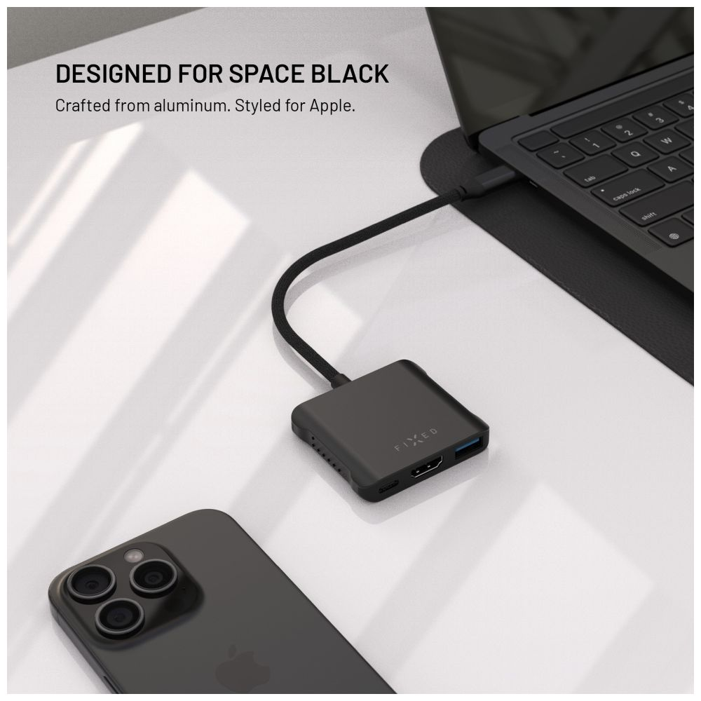 Ein schwarzer Hub und ein schwarzes Telefon. Es befindet sich auf einer weißen Oberfläche mit einem Laptop.