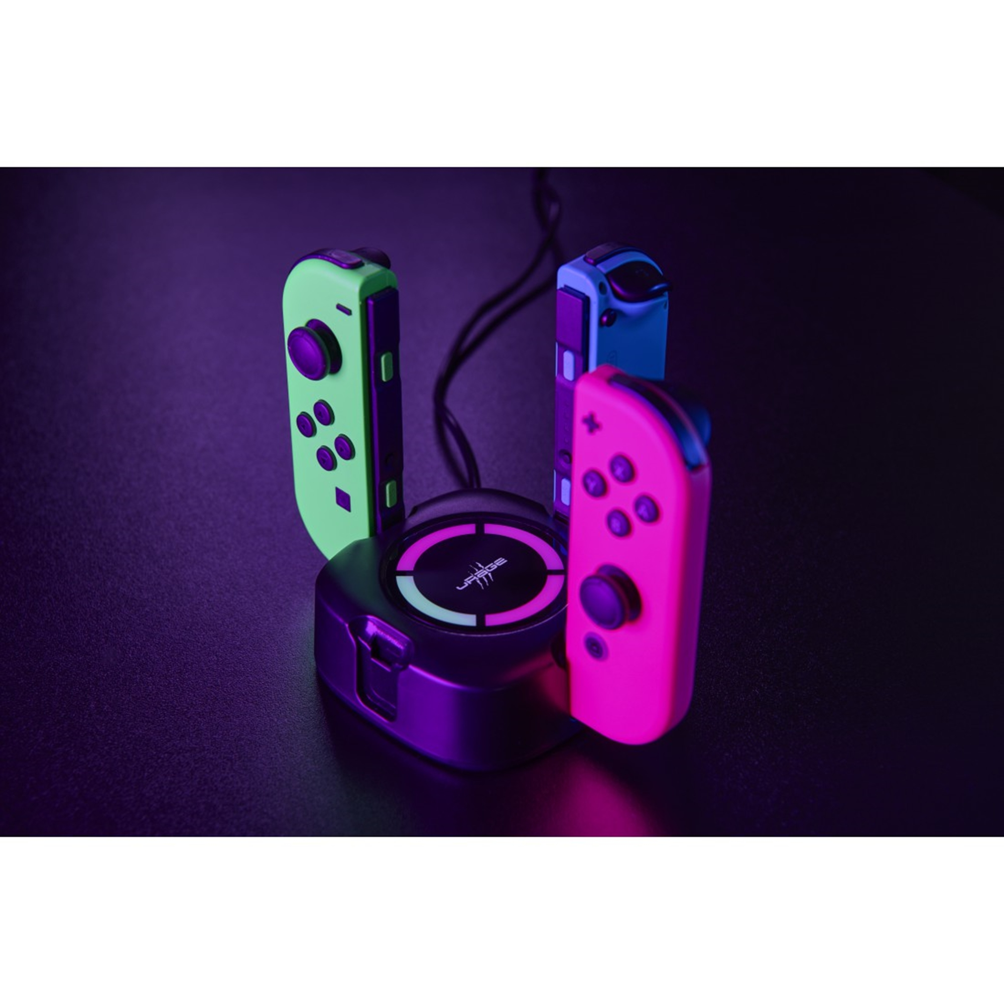 Eine Ladestation mit drei Gamecontrollern. Controller sind grün, rosa und blau. Dunkler Hintergrund.