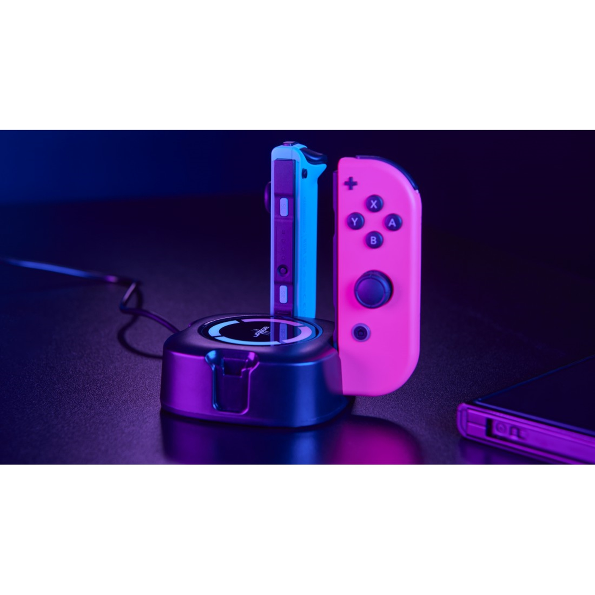 Eine Ladestation mit zwei Gamecontrollern. Controller sind rosa und blau. Dunkler Hintergrund.