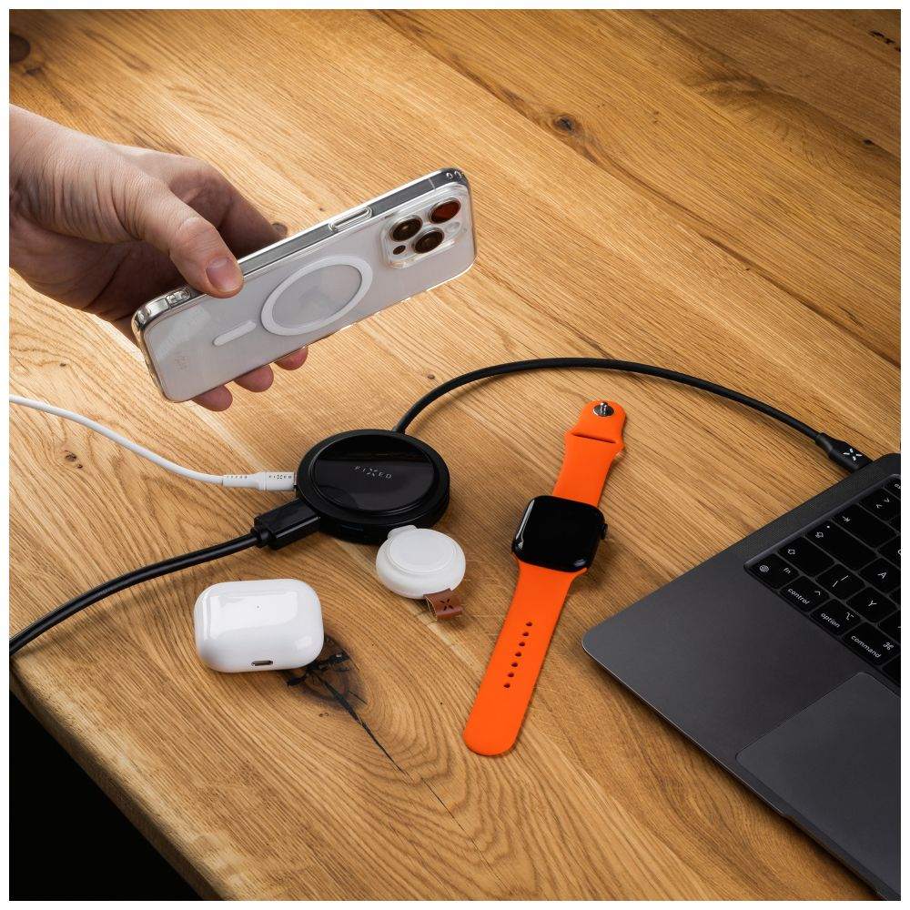 Holztisch mit Telefon, Ladepad, Smartwatch, Ohrhörern und Laptop.