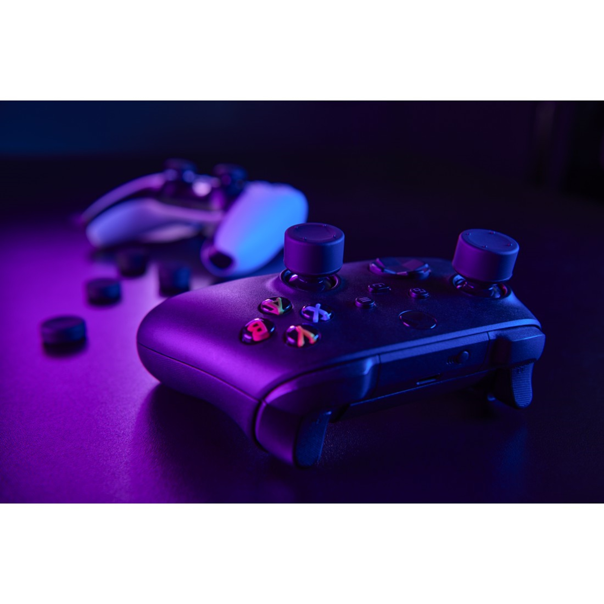 Ein schwarzer Gamecontroller mit blauer und violetter Beleuchtung. Zwei Controller sind sichtbar. Knöpfe und Joysticks sind zu sehen.