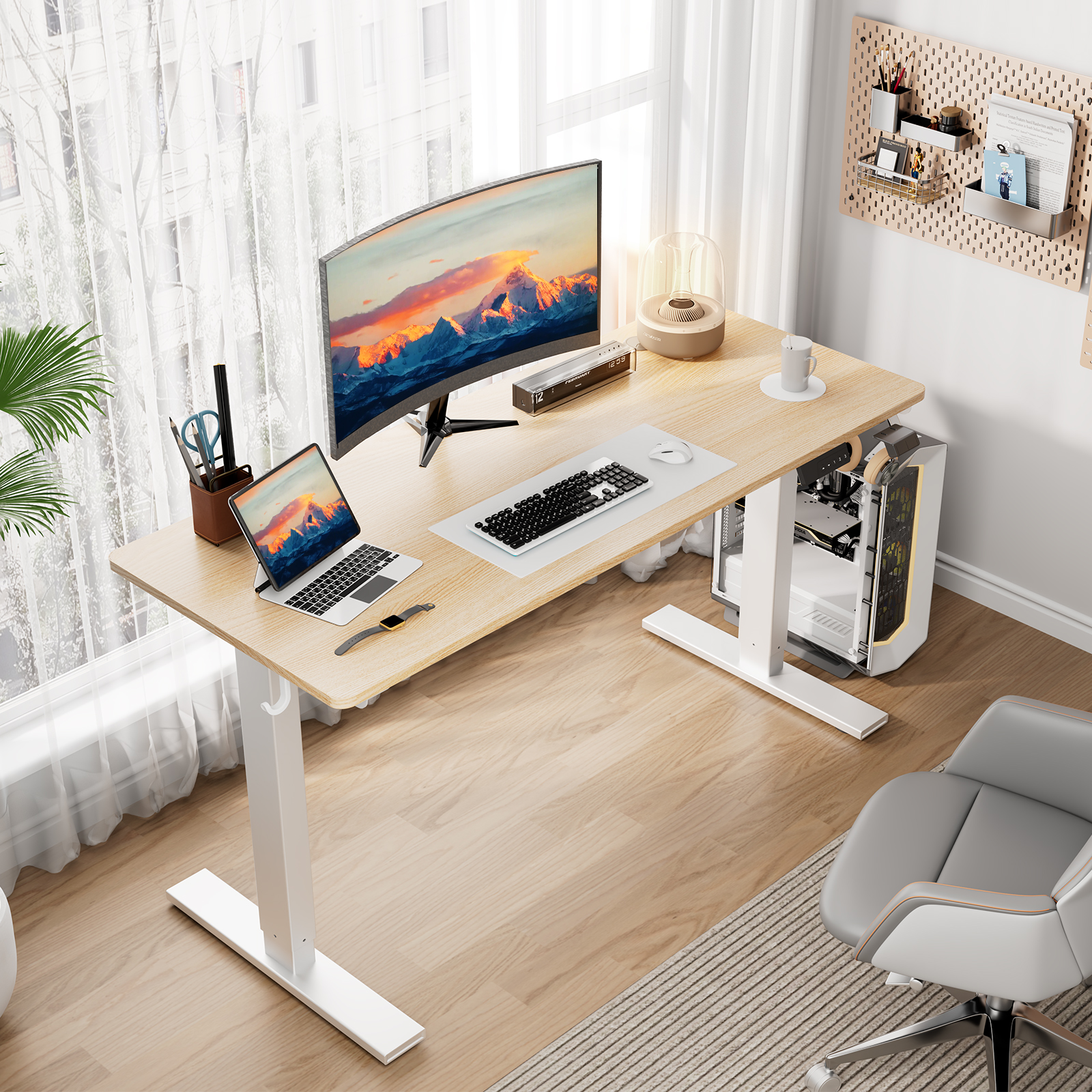 Ein gut beleuchtetes Heimbüro mit Schreibtisch, Computer und Zubehör. Ein Fenster und ein grauer Stuhl sind ebenfalls vorhanden.