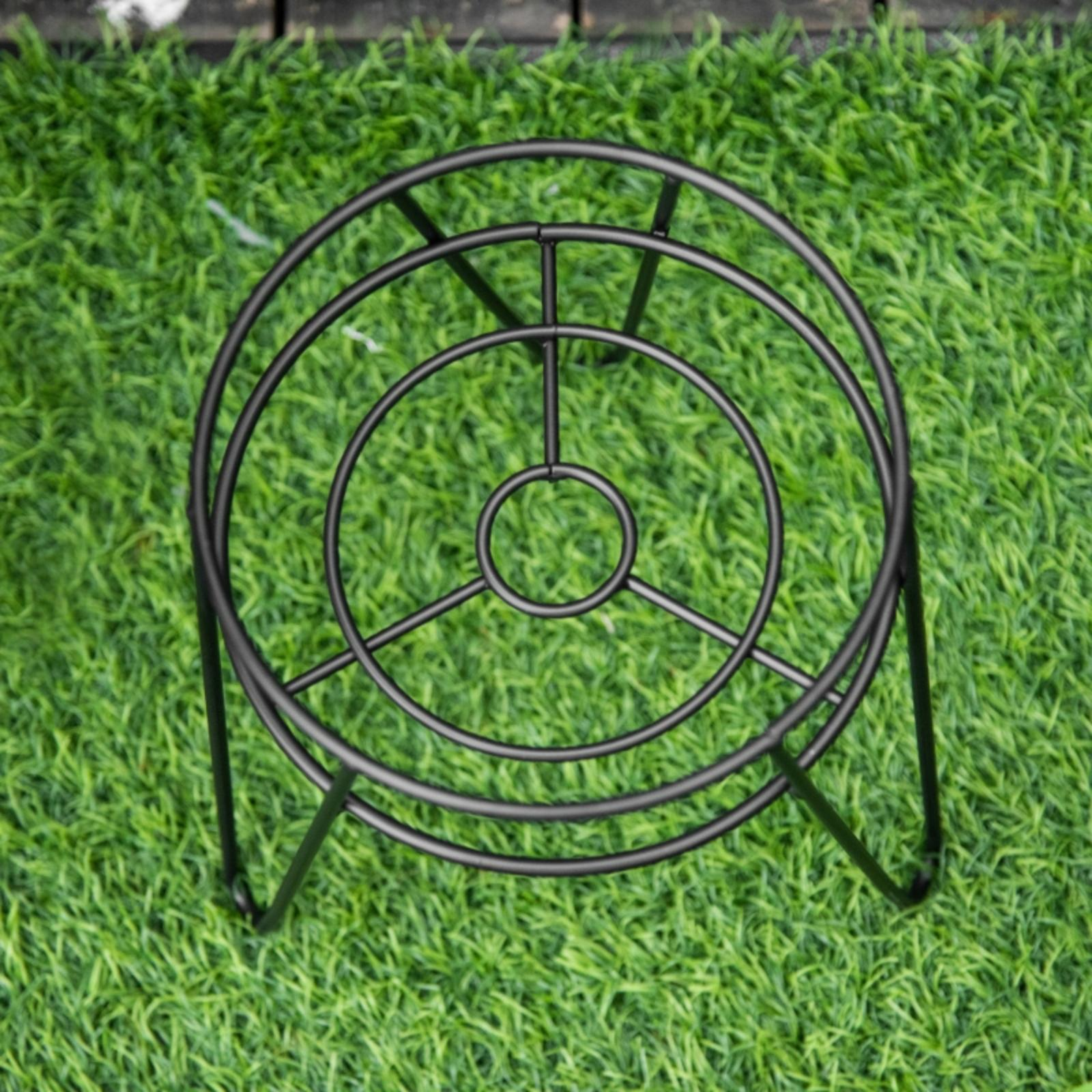 Draufsicht auf einen schwarzen Metall-Pflanzenständer auf grünem Gras. Der Ständer hat ein kreisförmiges Design.