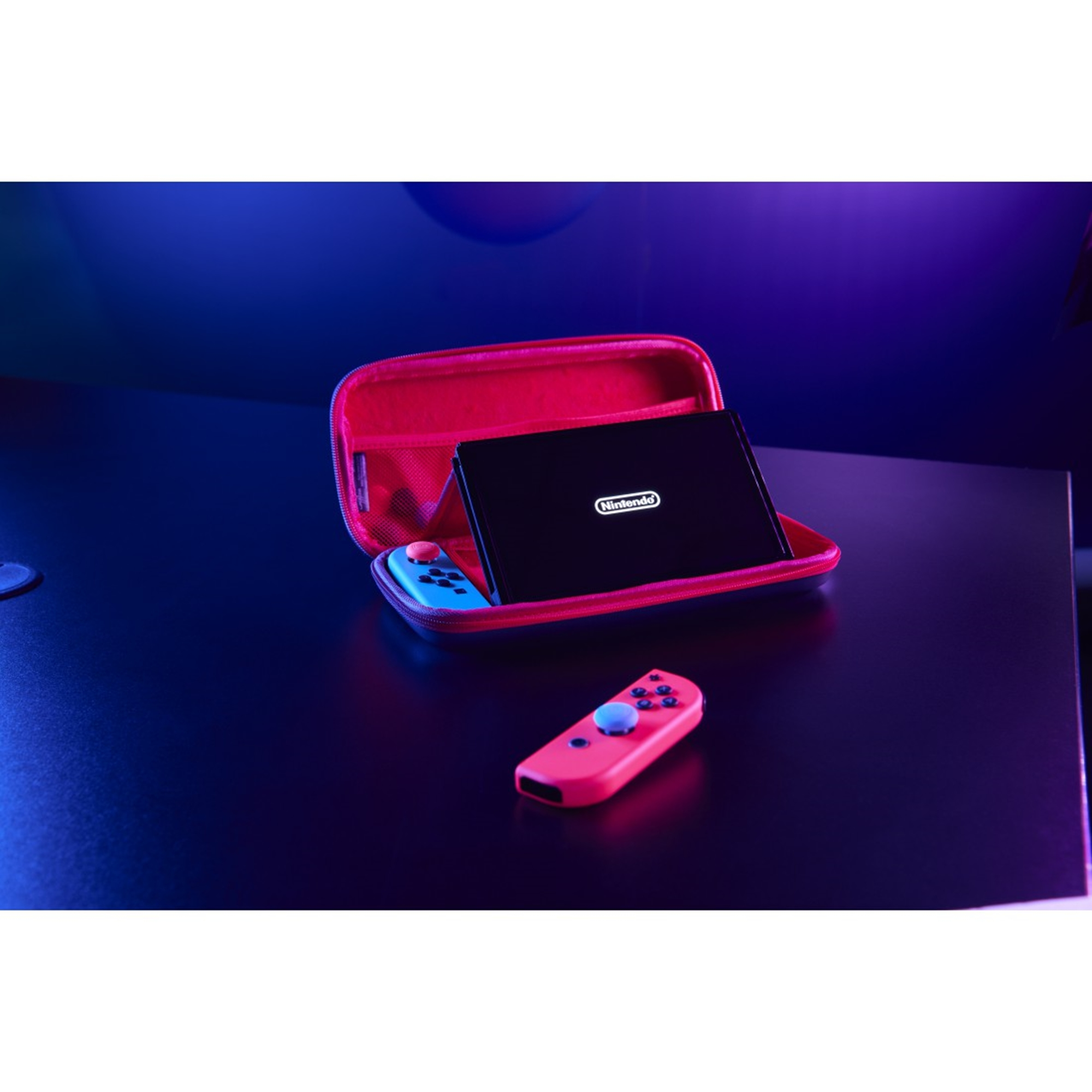 Eine rote Hülle mit einer Konsole und blau-roten Controllern auf dunkler Oberfläche mit blau-violettem Schein.