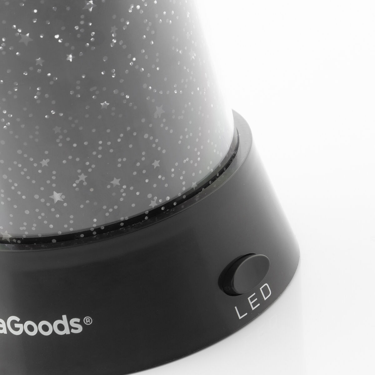 Lampada proiettore di stelle nera con un pulsante LED ed effetto cielo stellato su superficie bianca.