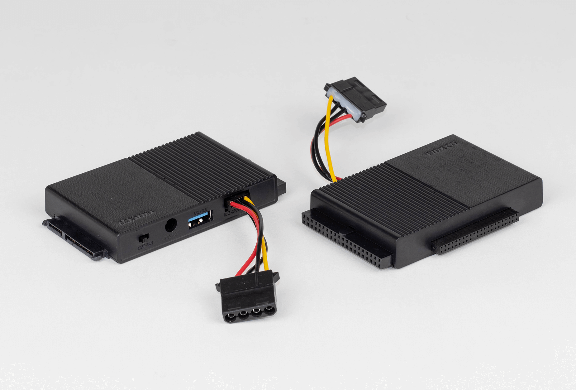 Dwa czarne adaptery dysku twardego z kablami. Jeden ma port USB, a drugi wiele pinów złącza.