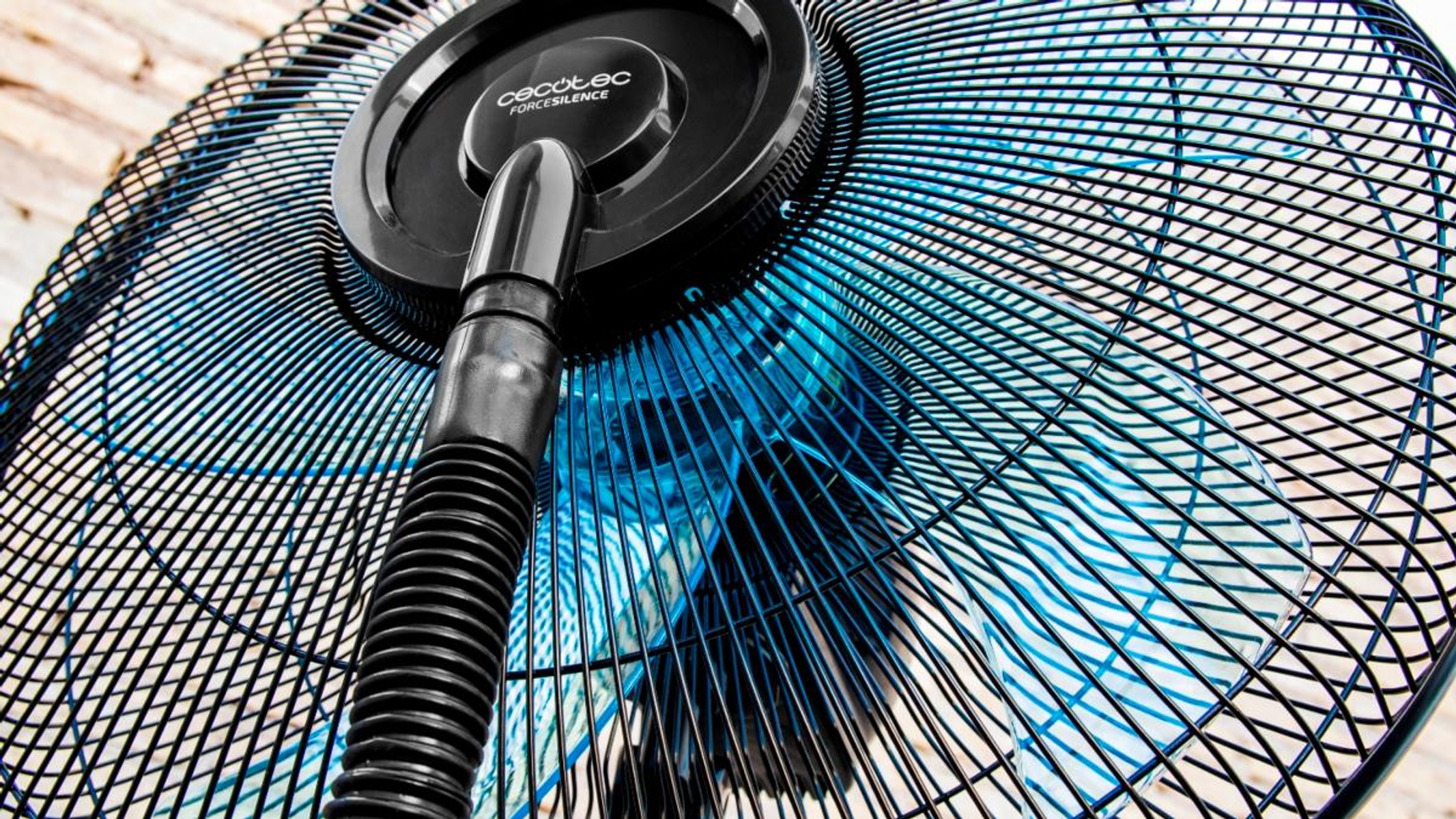 Vista de cerca desde abajo de un ventilador negro con aspas azules, mostrando la estructura interna.