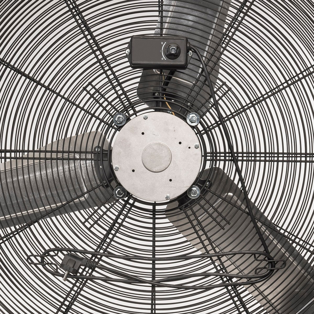 Vista dall'alto di un ventilatore con tre pale, racchiuso in una gabbia di metallo nero. C'è un pannello di controllo in alto. È visibile un cavo di alimentazione.