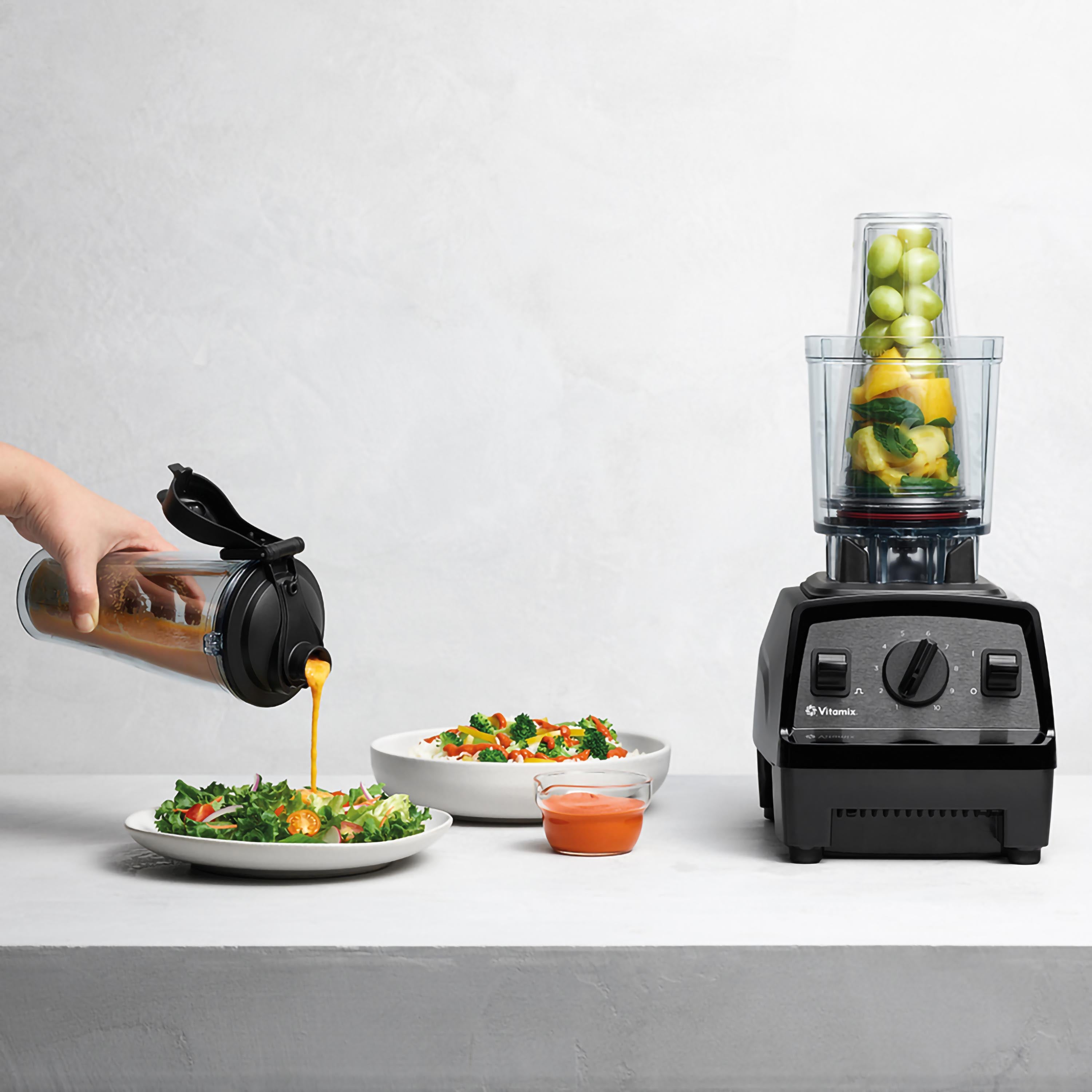 Eine Person gießt Smoothie aus einem Behälter in eine Schüssel. Ein Mixer steht rechts.