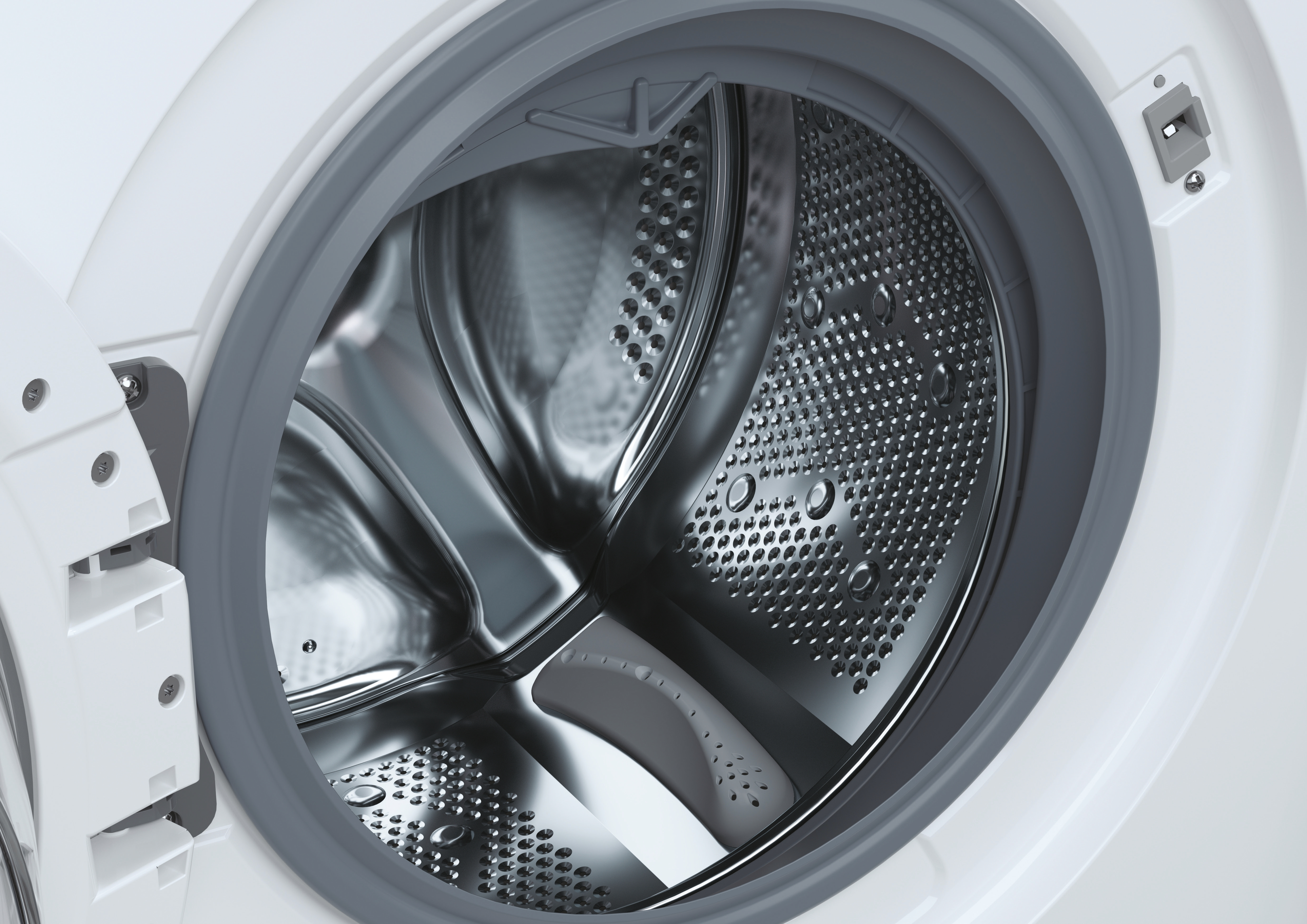 Primo piano del cestello di una lavatrice, interno in acciaio inox con fori.