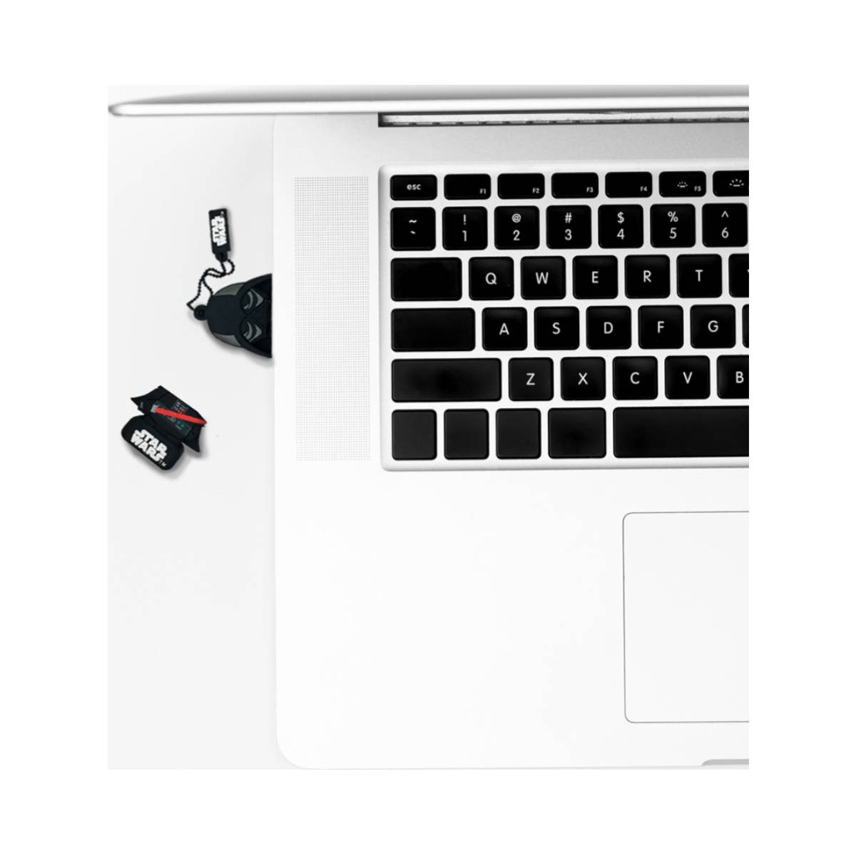 Laptop-Tastatur, Star-Wars-Zubehör auf weißer Oberfläche. Schwarze Tasten, Star-Wars-Aufkleber und ein schwarzer Helm.