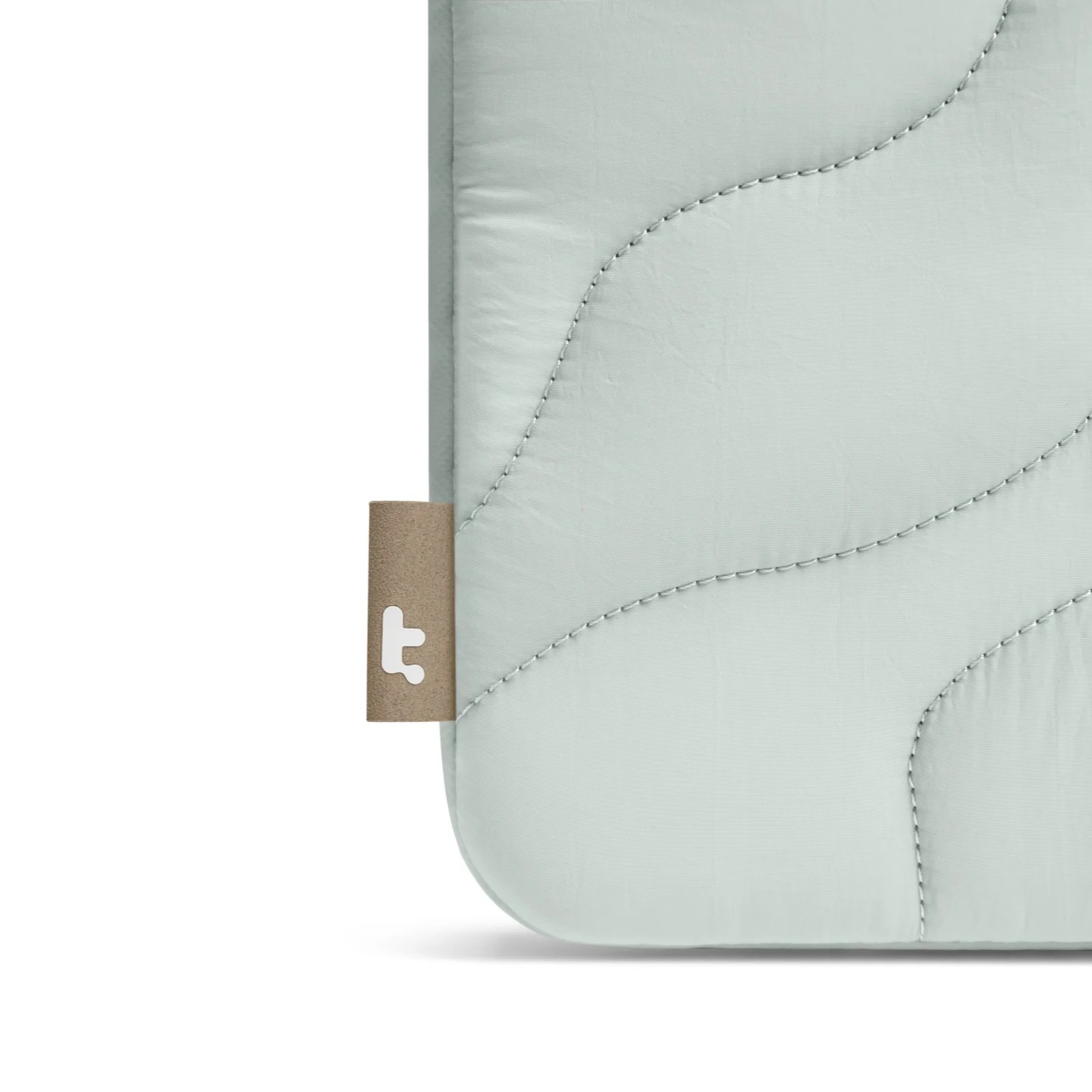 Zbliżenie rogu jasnozielonej osłony na laptopa z brązową etykietą. Białe tło.