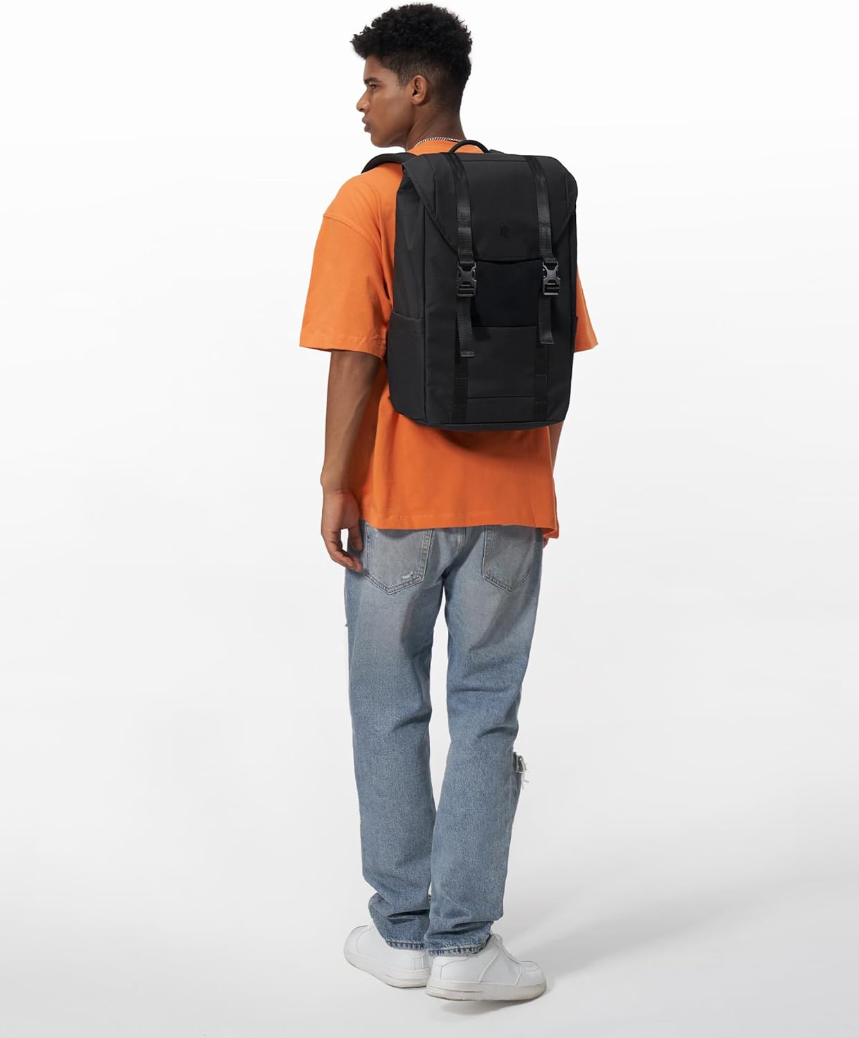Mężczyzna w pomarańczowej koszuli i niebieskich dżinsach z czarnym plecakiem na plecach.