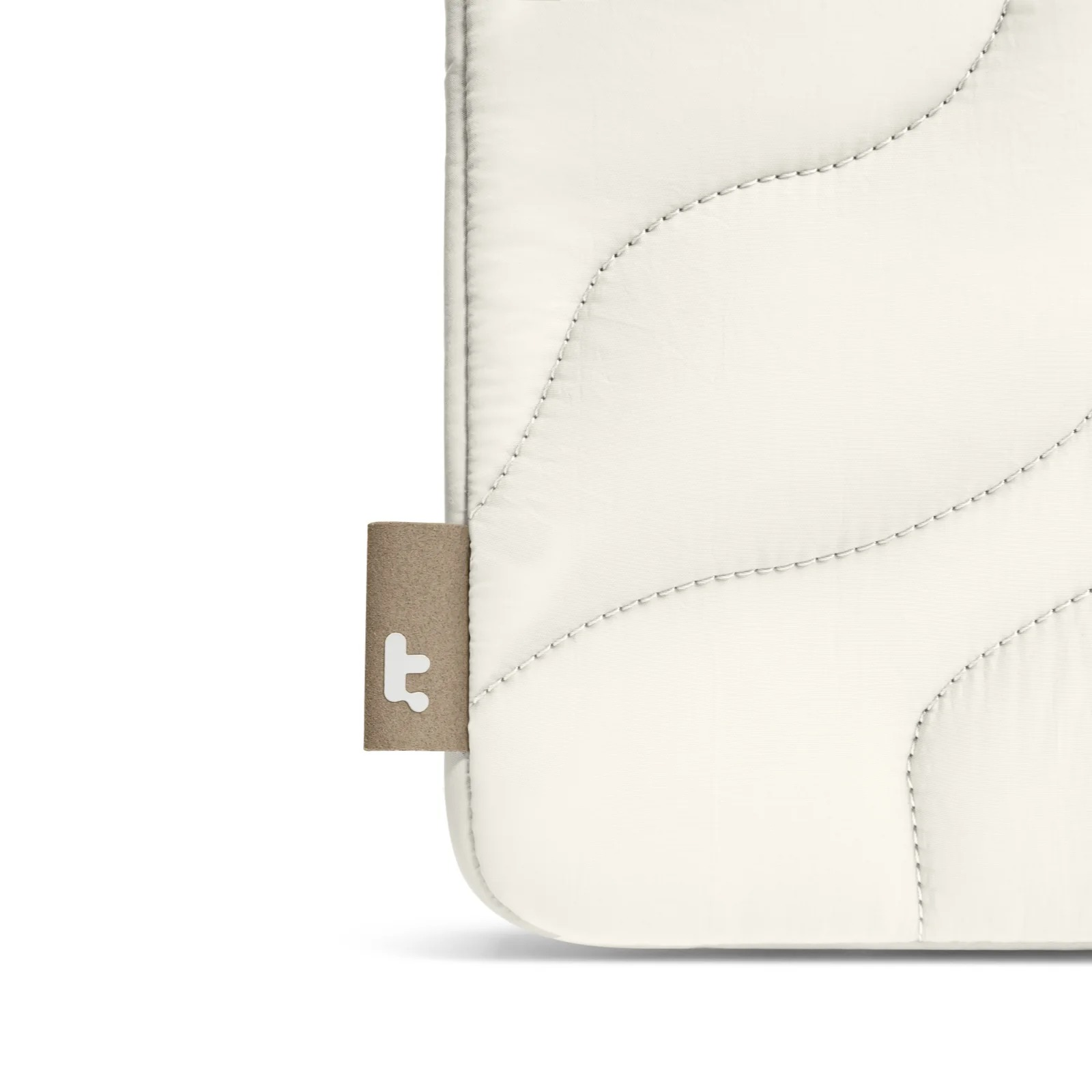 Zbliżenie białej pikowanej osłony na laptopa z brązową metką z logo. Widoczny wzór szwów.