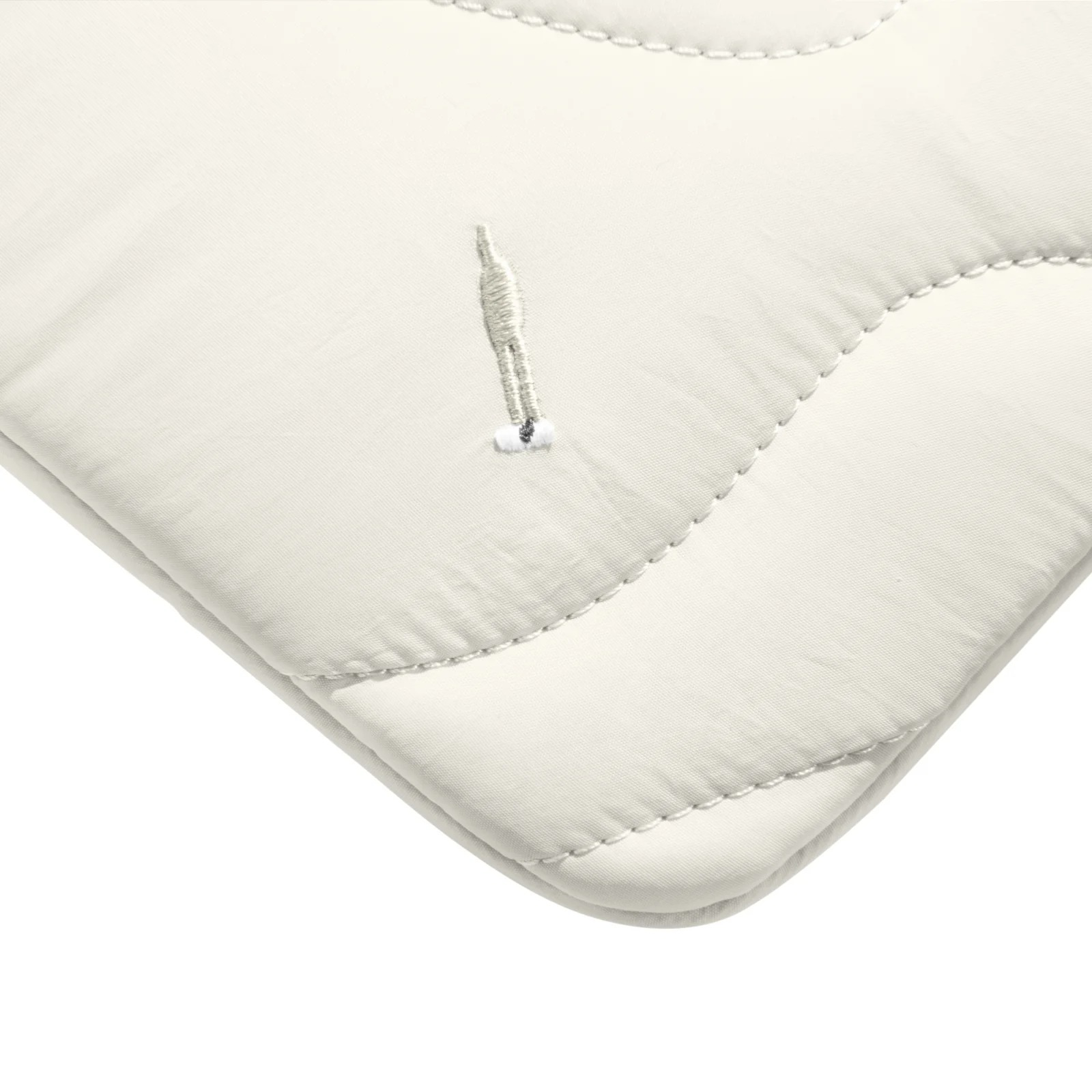 Zbliżenie pokazuje róg białej pikowanej torby na laptopa. Widoczne są szwy i małe logo.