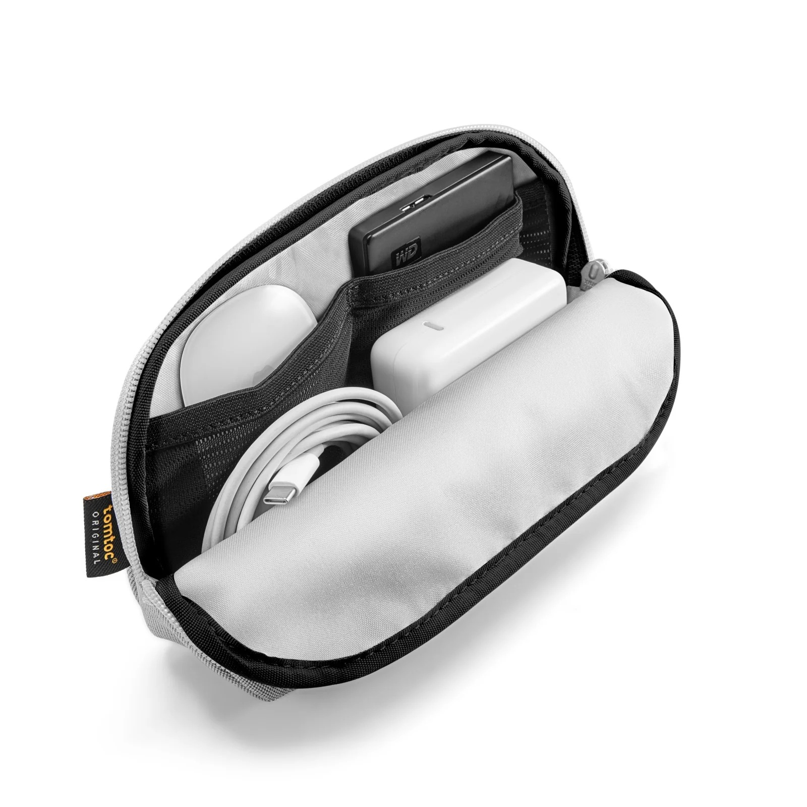 Otwarta szara obudowa z myszą, ładowarką, dyskiem twardym i kablem w środku. Obudowa leży na białej powierzchni.