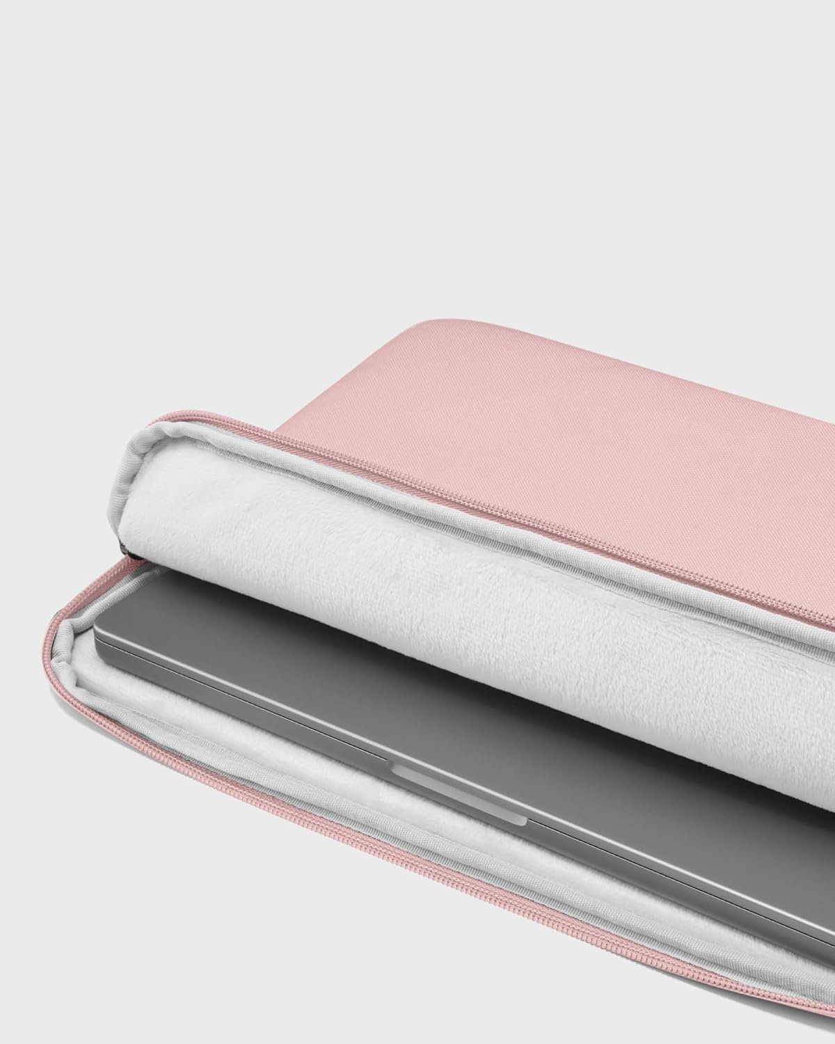 Otwarta różowa torba na laptopa, ujawniająca srebrny laptop w środku. Widoczne białe, puszyste wnętrze.
