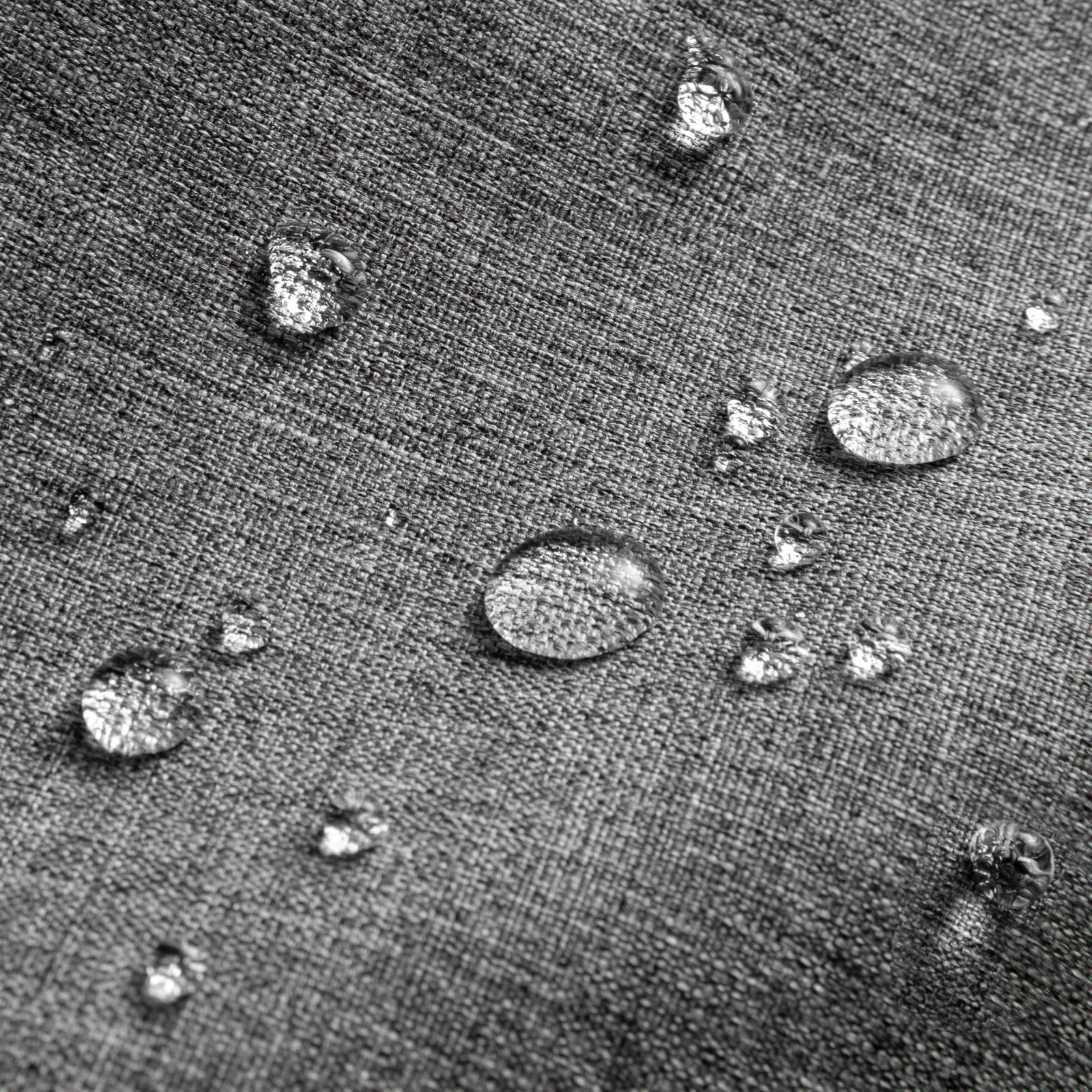 Zbliżenie kropli wody na szarej, teksturowanej tkaninie. Krople są różnej wielkości, niektóre odbijają światło.