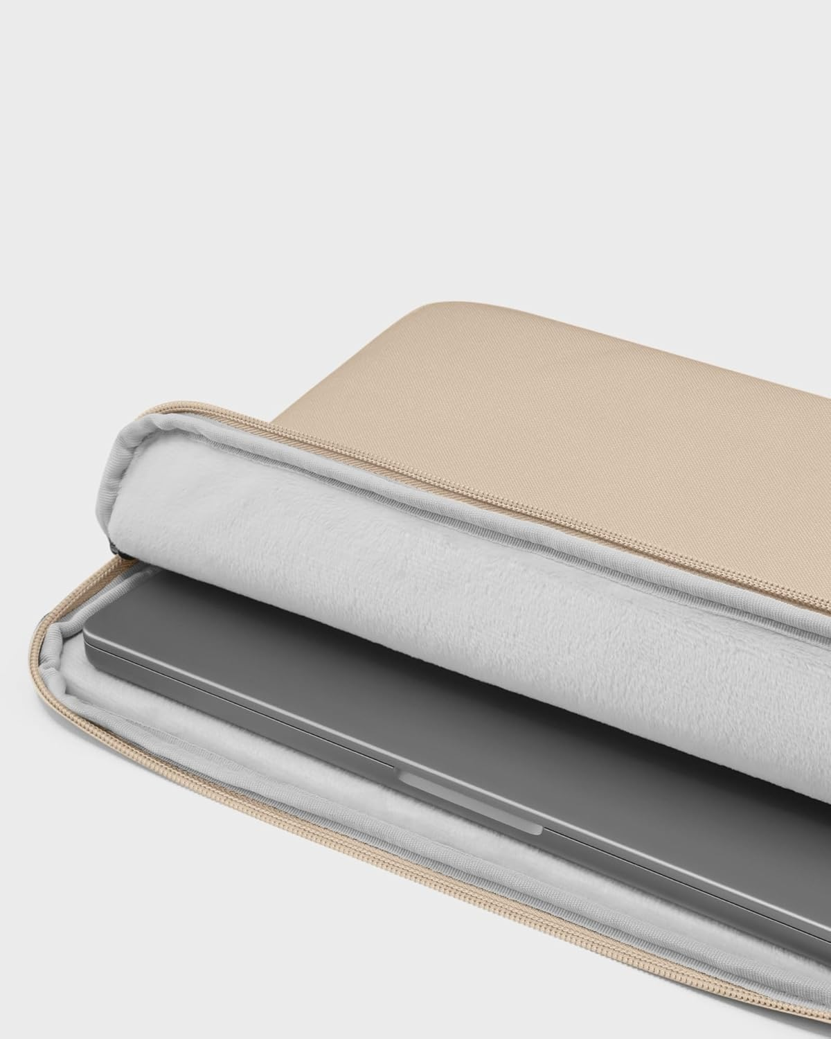 Beżowa torba na laptopa otwarta ze srebrnym laptopem w środku. Wnętrze jest białe.
