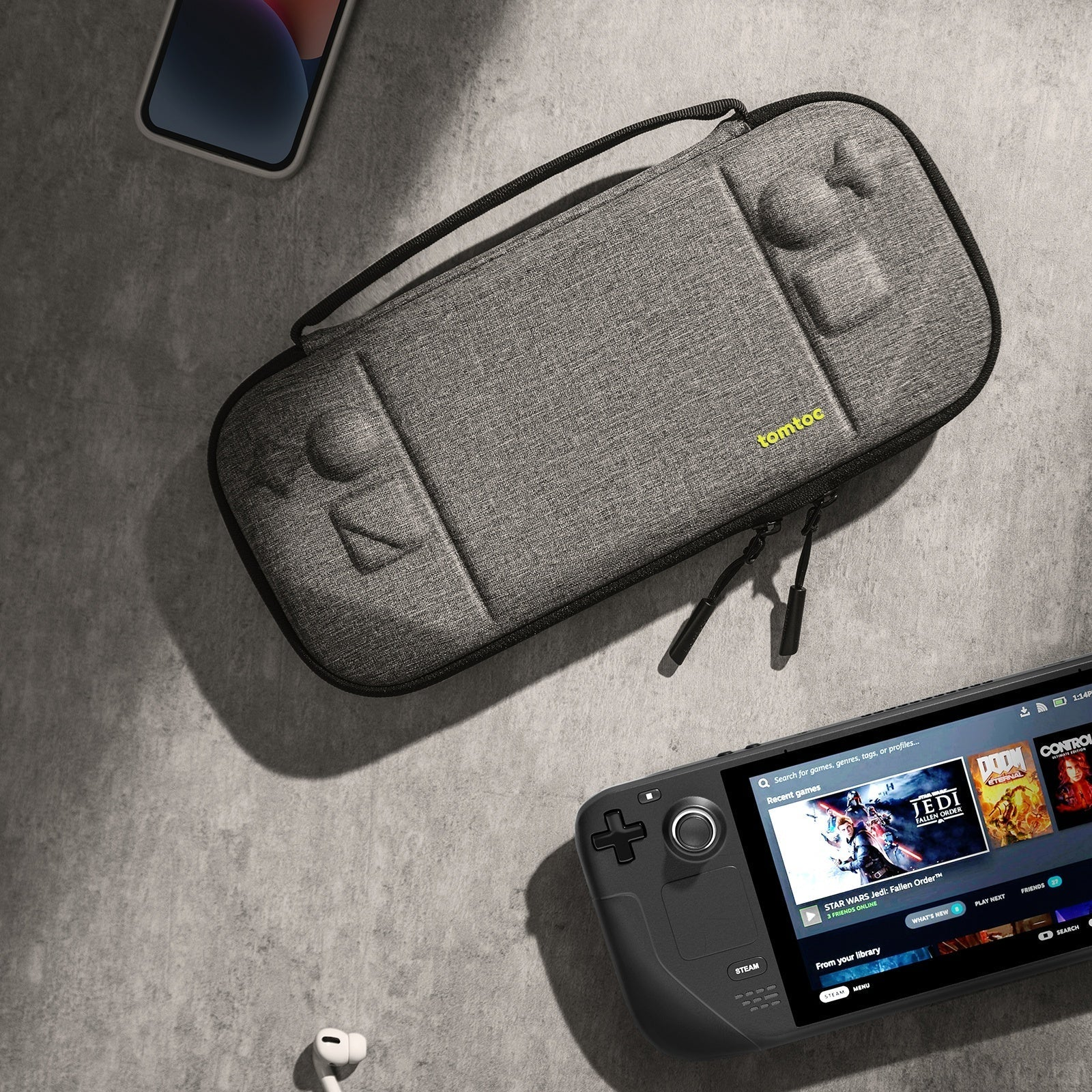 Szare etui, szary Steam Deck i biały telefon na powierzchni.