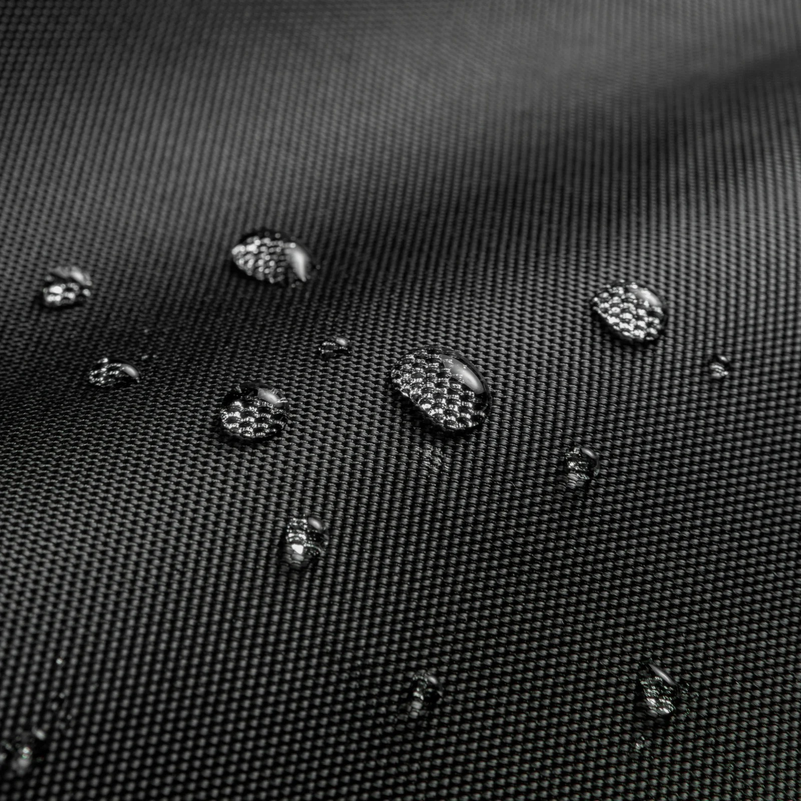 Zbliżenie czarnej, odpornej na zalanie tkaniny z kroplami wody.