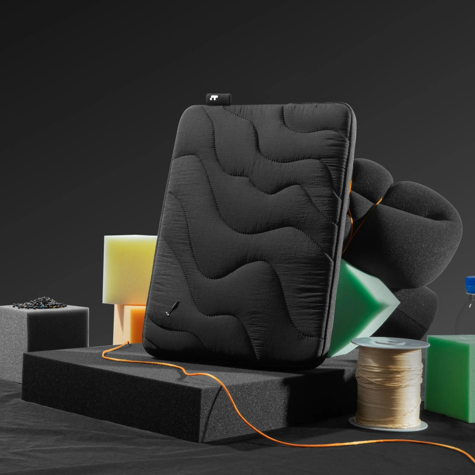 Czarna torba na laptopa z falistymi szwami, na czarnych i żółtych blokach piankowych.