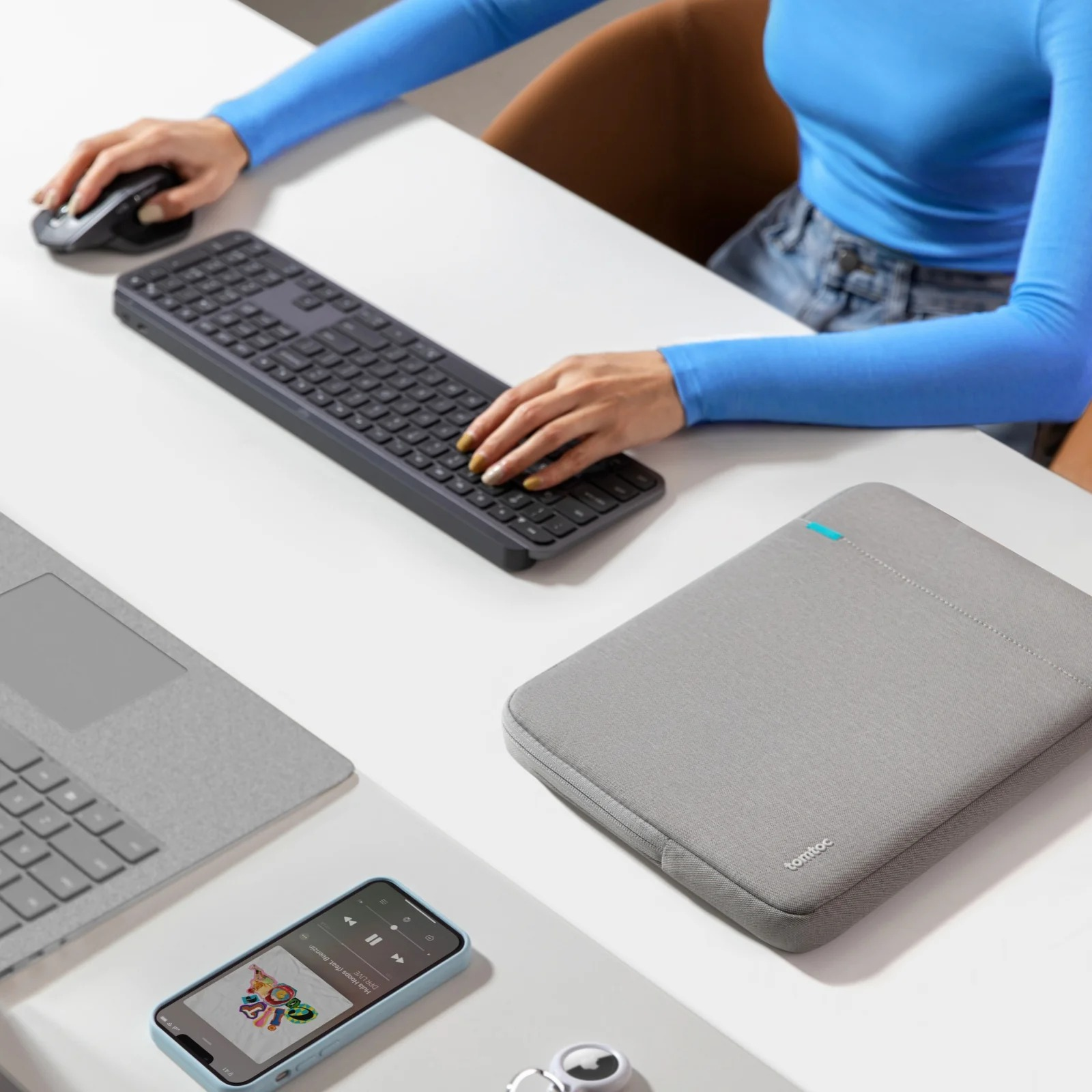 Osoba korzystająca z konfiguracji komputera. Laptop, klawiatura, mysz, telefon i szara torba na laptopa.