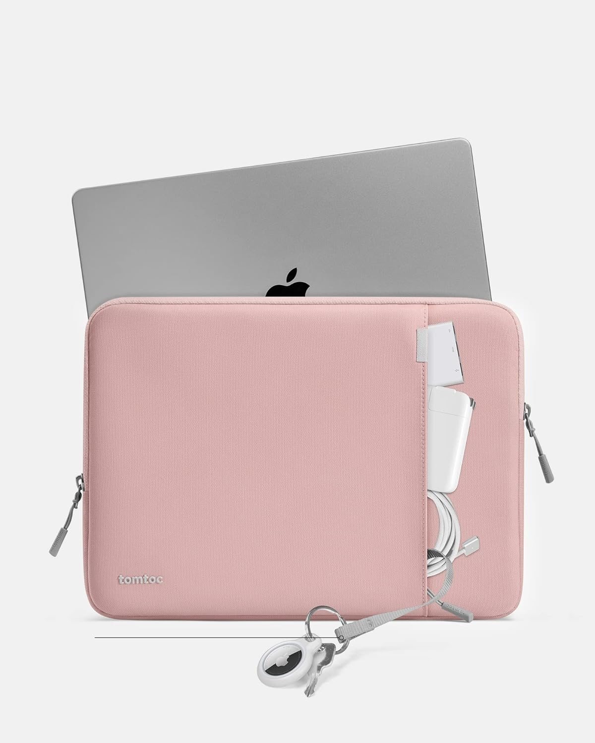 Różowa torba na laptopa z laptopem, ładowarką i kluczami. Białe tło.