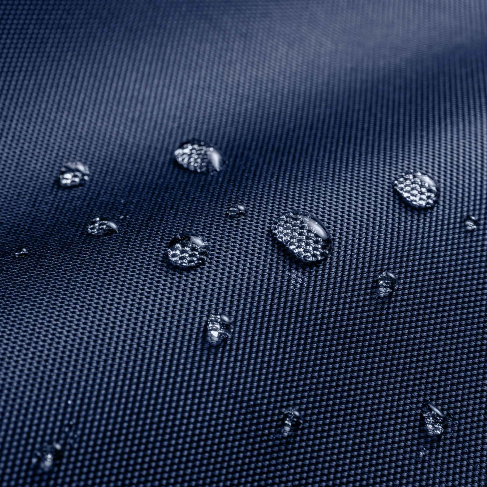 Zbliżenie kropli wody na granatowej, teksturowanej powierzchni.