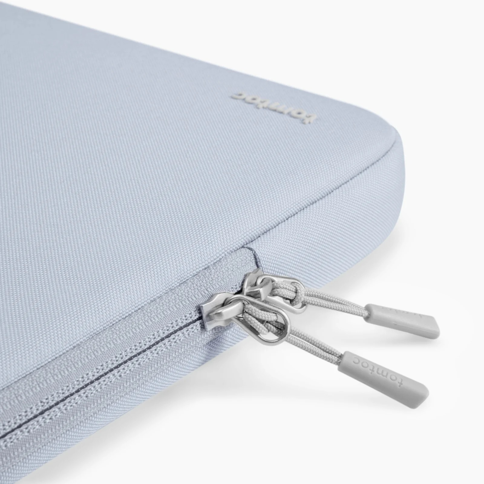 Jasnoniebieskie etui na laptopa z zamkami błyskawicznymi i logo Tomtoc.