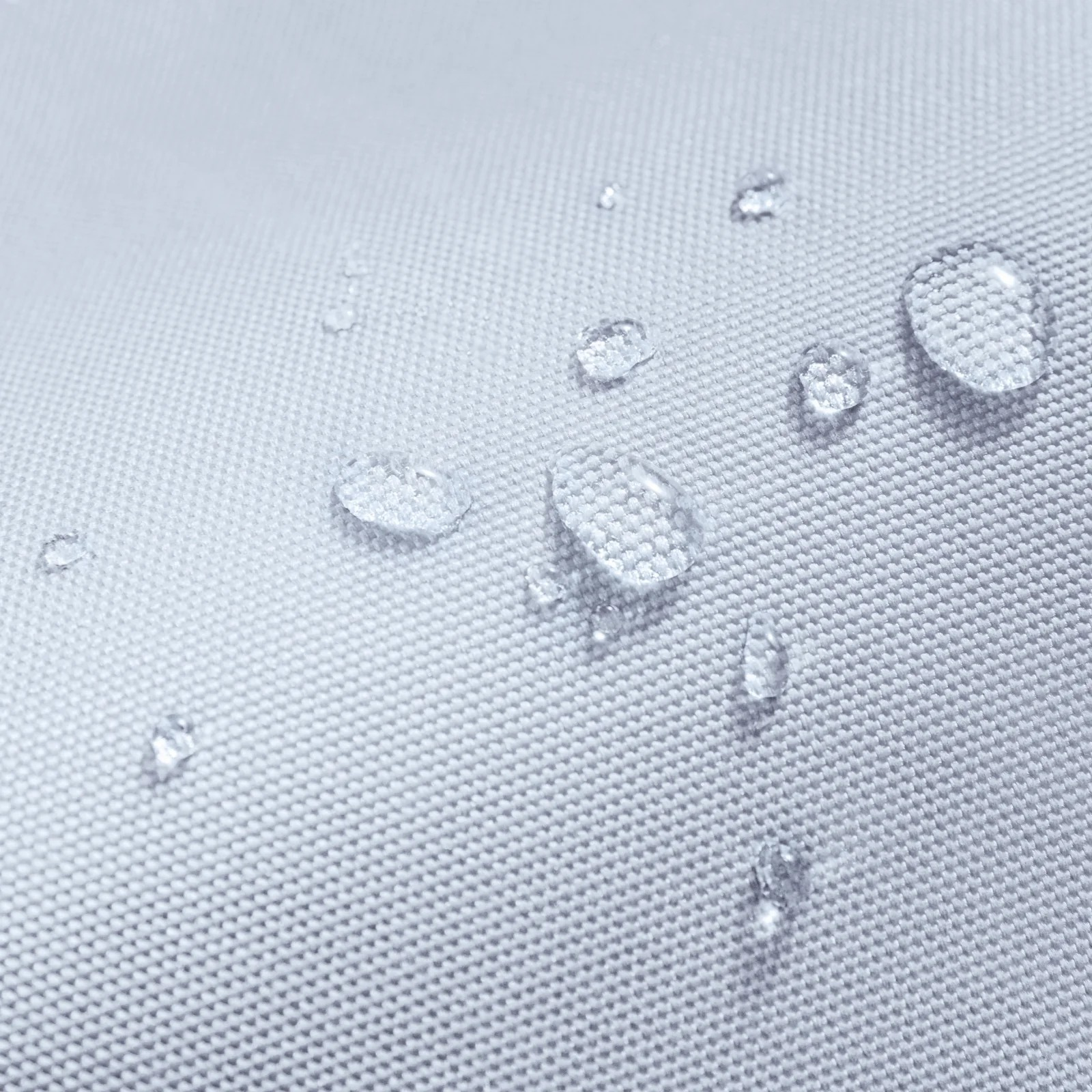 Zbliżenie kropli wody na jasno szarej tkaninie.