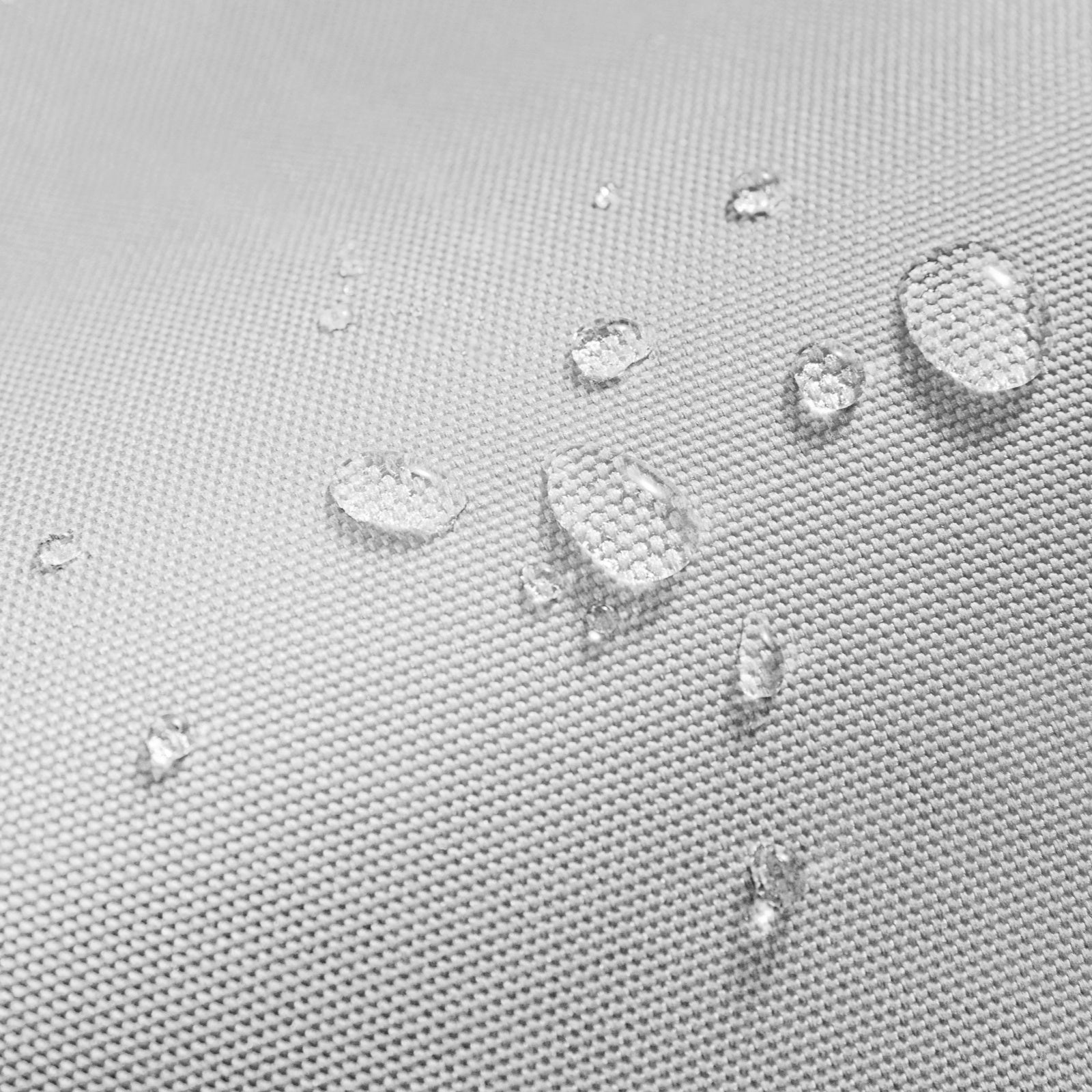 Zbliżenie kropelek wody na jasnoszarej powierzchni materiału. Materiał ma wzór tekstury.