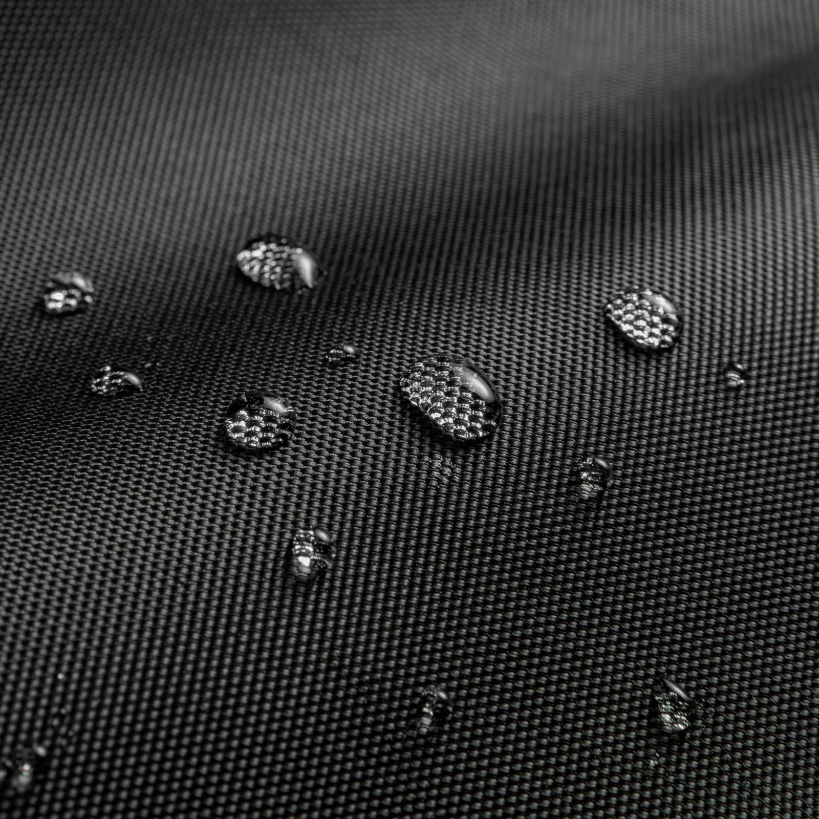 Zbliżenie czarnej tkaniny z kroplami wody. Krople są przejrzyste i odbijające światło.