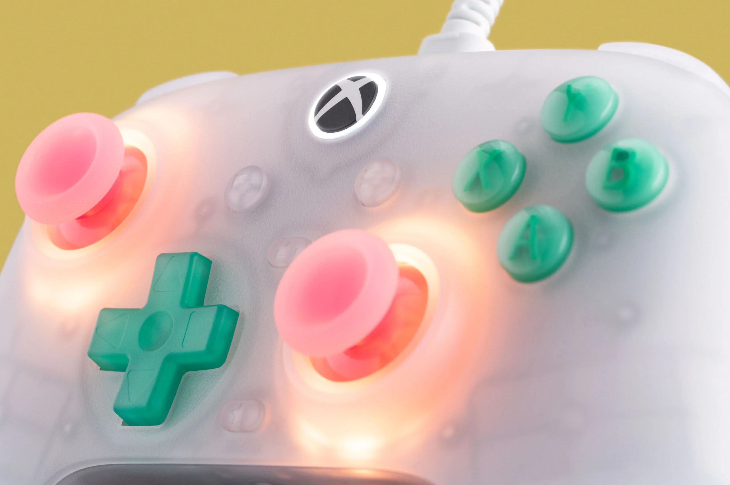 Primo piano di un controller bianco con pulsanti rosa e verdi, illuminato.